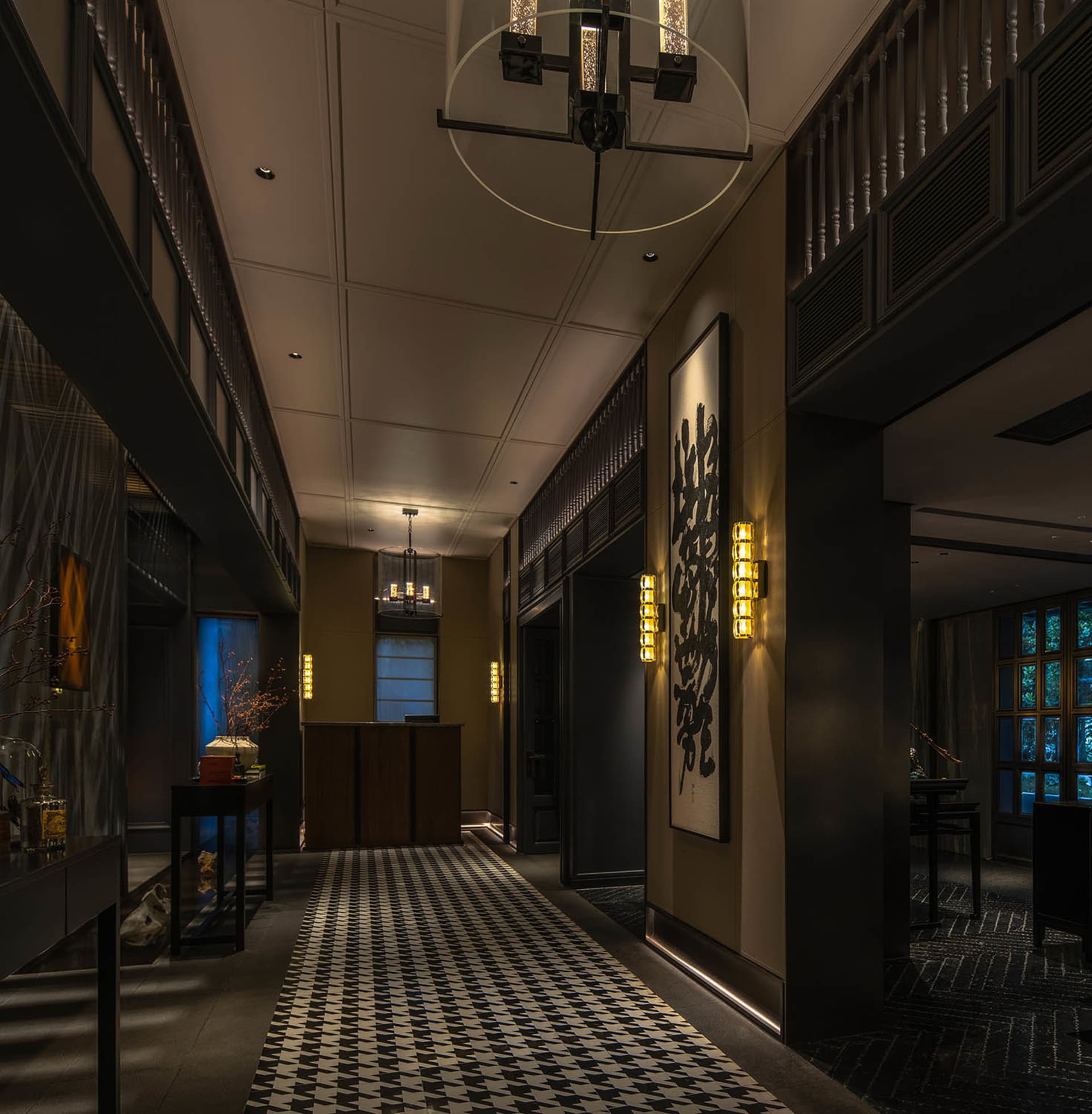 A hotel lobby with a checkered tile floor, a large chandelier, potted plants, and decorative vases create a stylish and inviting atmosphere