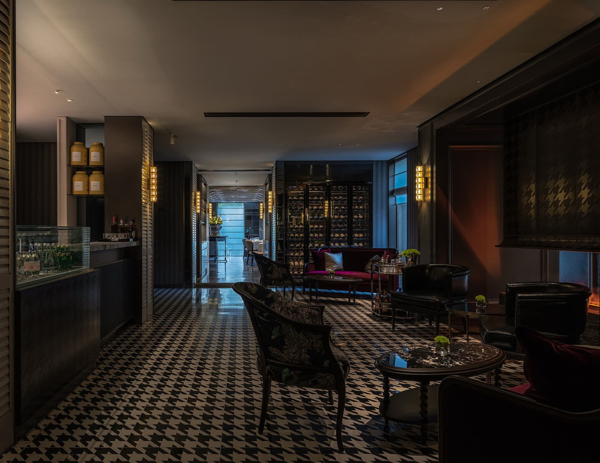 A modern and sophisticated hotel lobby with a black and white checkered floor, featuring various pieces of furniture and decorative bottles