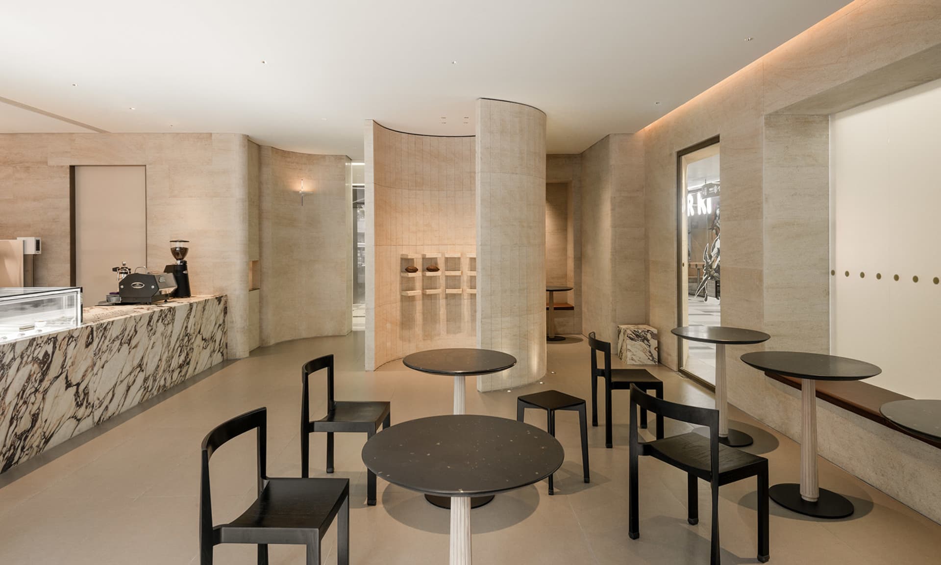 A modern dining area with a large circular table and black chairs, dimly lit for a cozy ambiance
