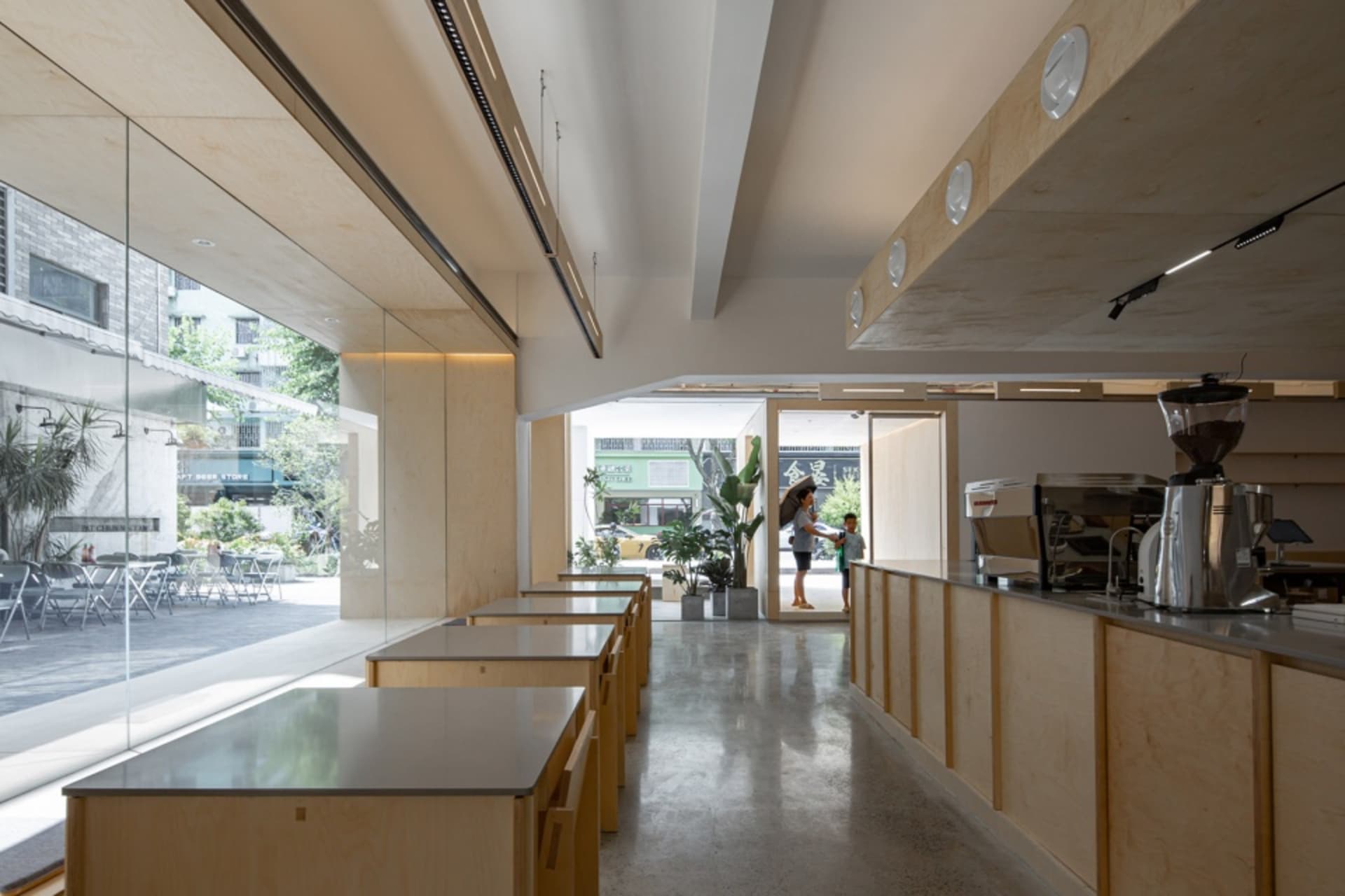 明亮吸引人的餐廳空間，排列著現代木桌，並有大窗戶讓陽光灑入