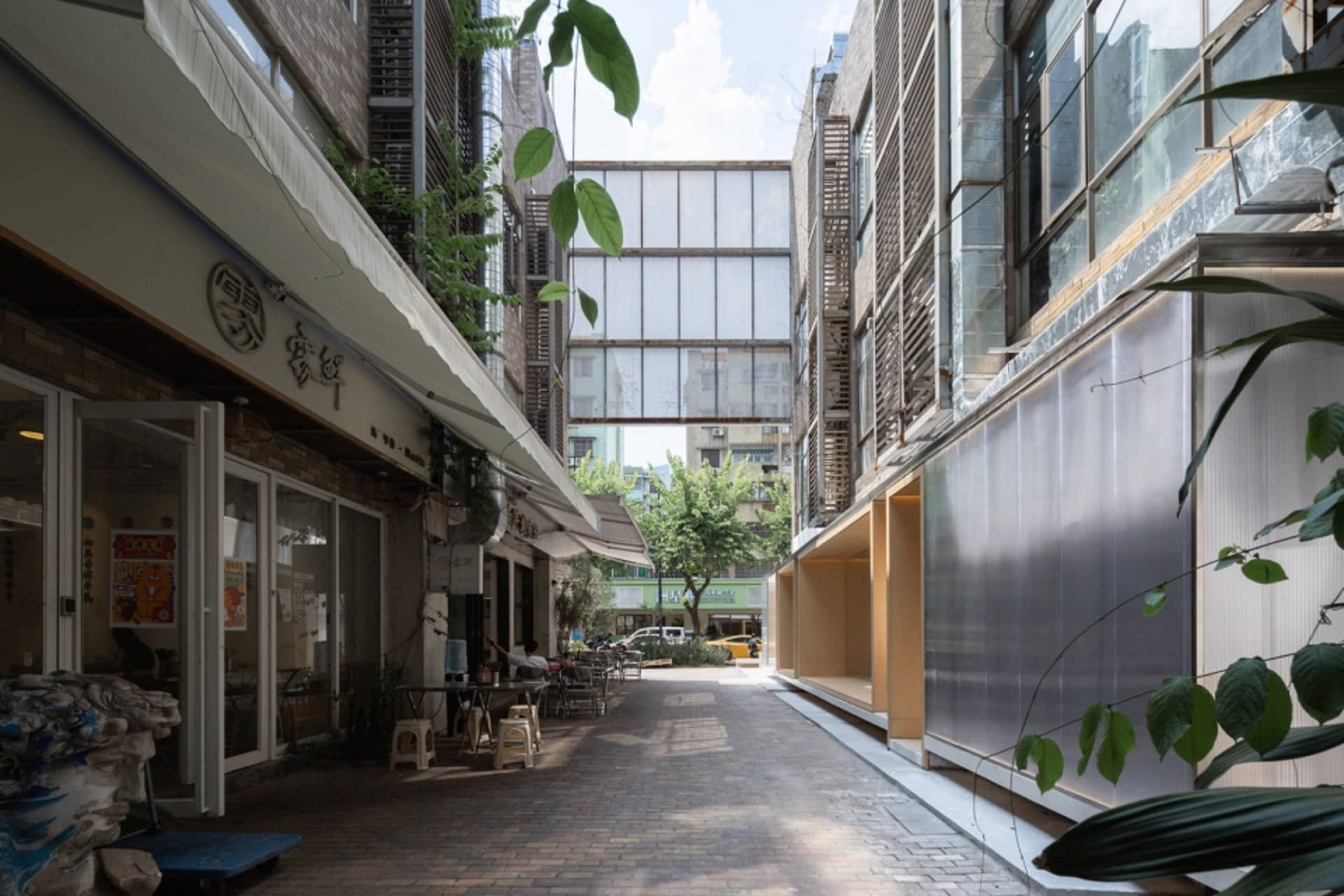 A vibrant city street scene with modern buildings, glass windows, and outdoor seating areas with bicycles parked nearby