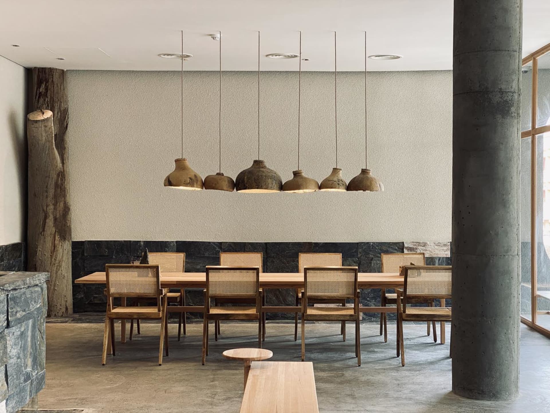 A modern dining area with a wooden floor, dim lighting, and decorative vases above the table
