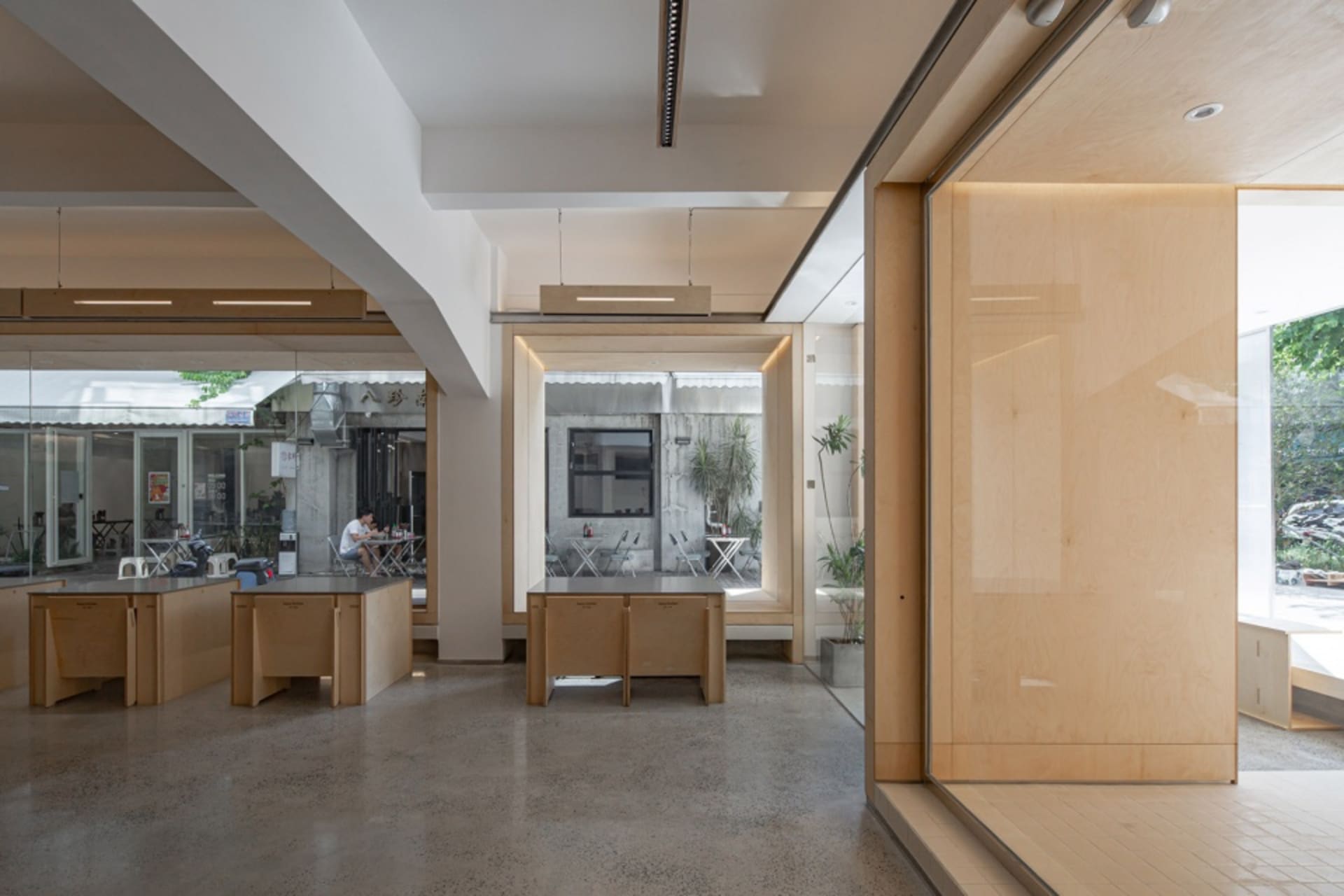 Open office space with natural light, chairs, a dining table, and potted plants