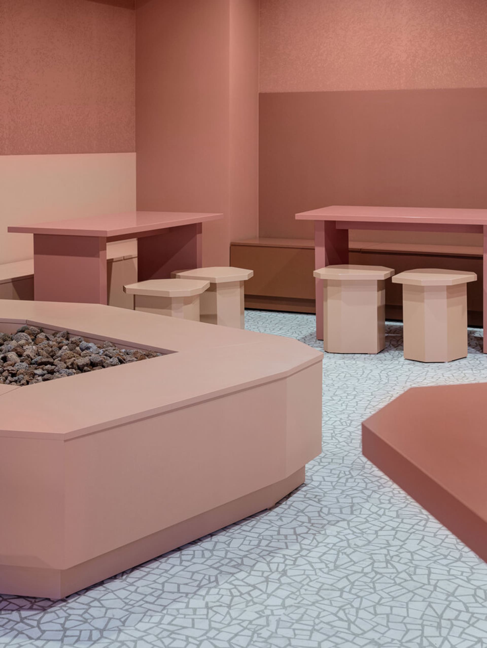 Cozy cafe interior with pink walls, wooden furniture, and a fireplace, creating a warm atmosphere for dining and socializing