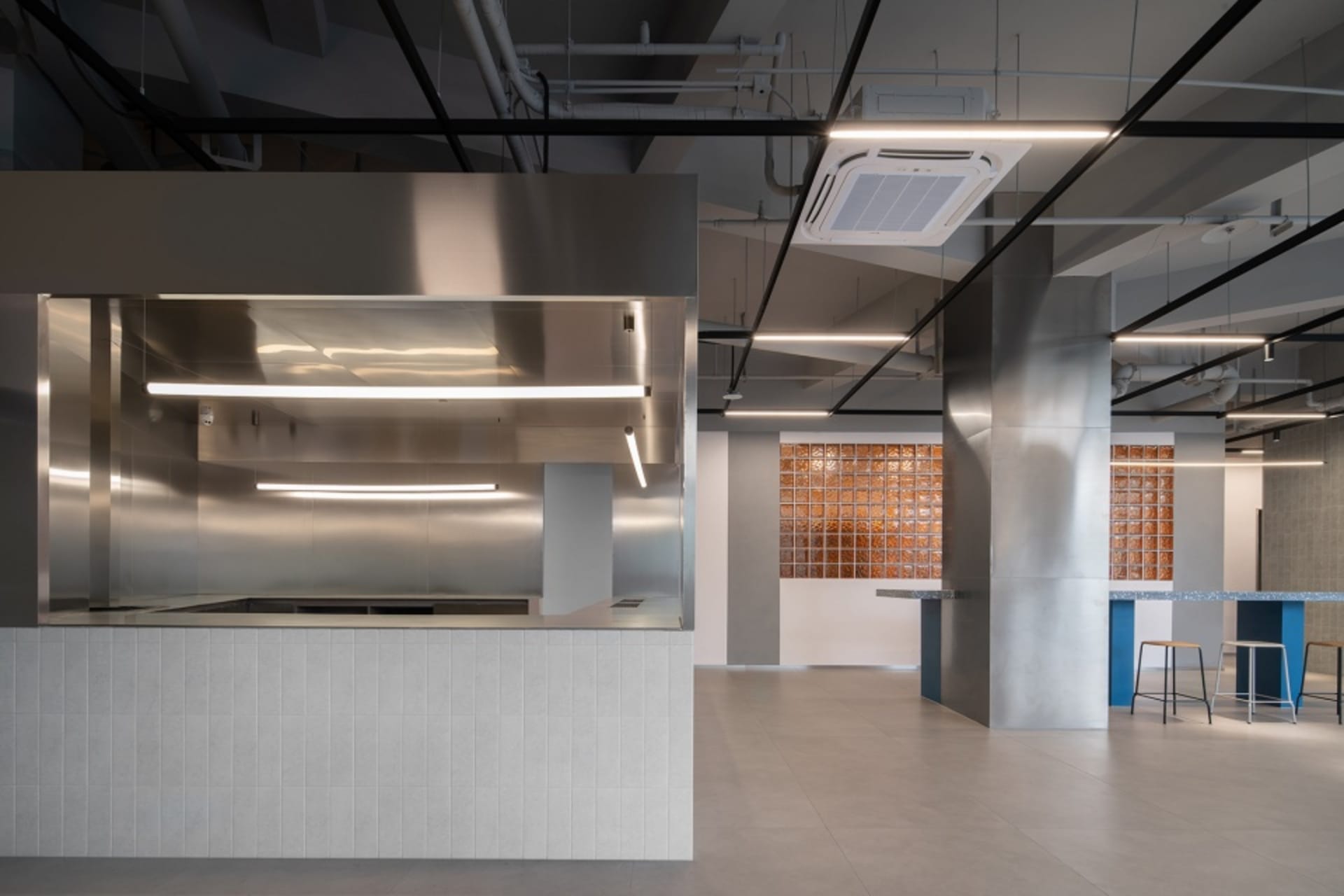 Industrial kitchen with stainless steel surfaces and tile flooring, featuring two sinks and ample countertop space
