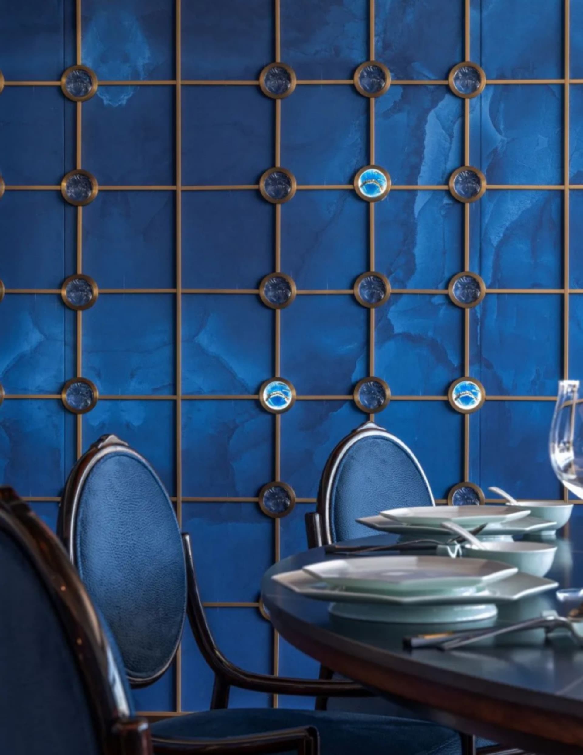 Dining area with a table and chairs, surrounded by a unique circular wall design, with plates on the table suggesting recent use