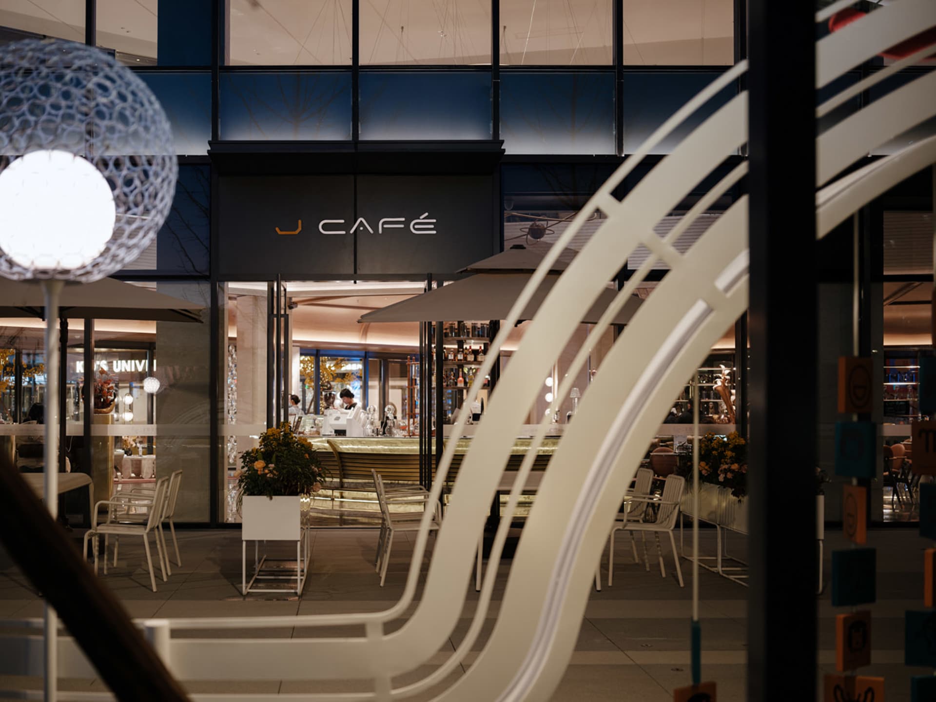 A modern cafe with several tables and chairs, white walls, and an inviting atmosphere