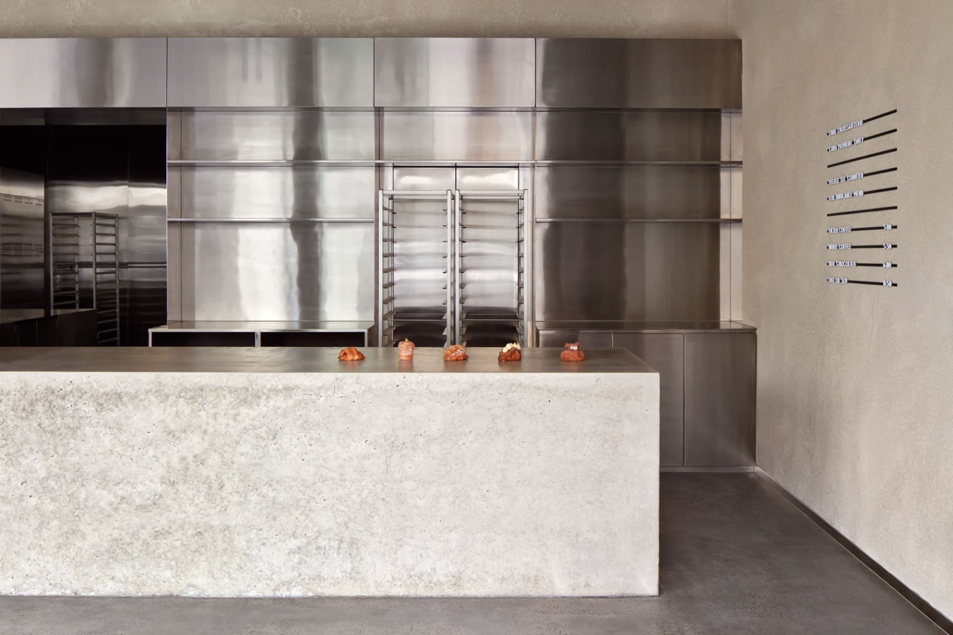 Industrial kitchen with stainless steel surfaces, two sinks, and various kitchenware on countertops
