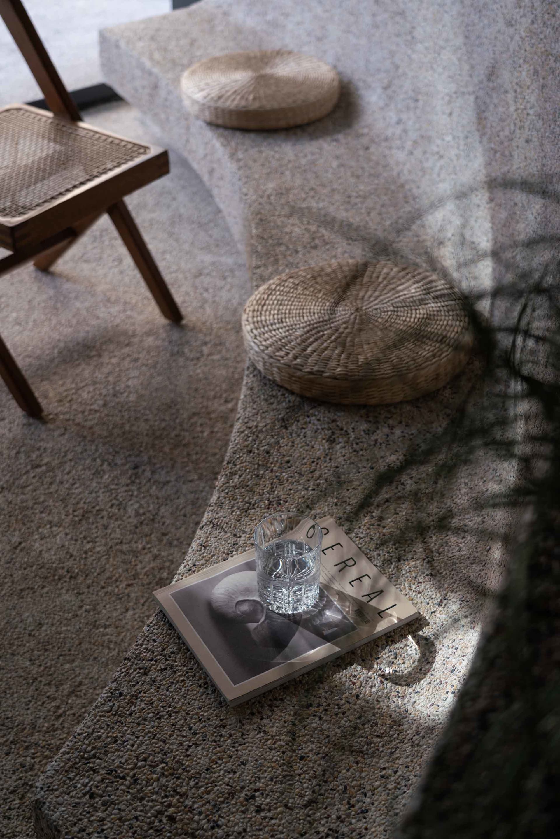 Cozy living area with a rugged floor, two chairs, a book, a cup, and a potted plant