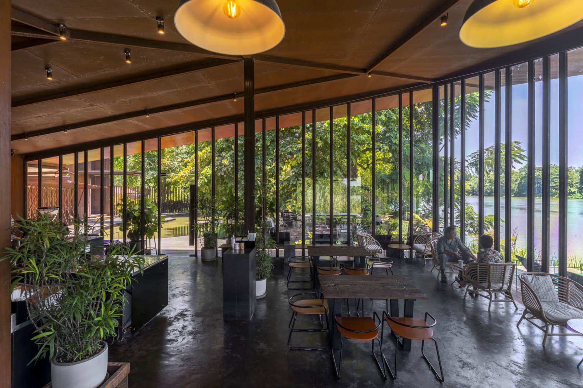 Dining area with chairs, cushions, potted plants, and a large window allowing natural light to enter