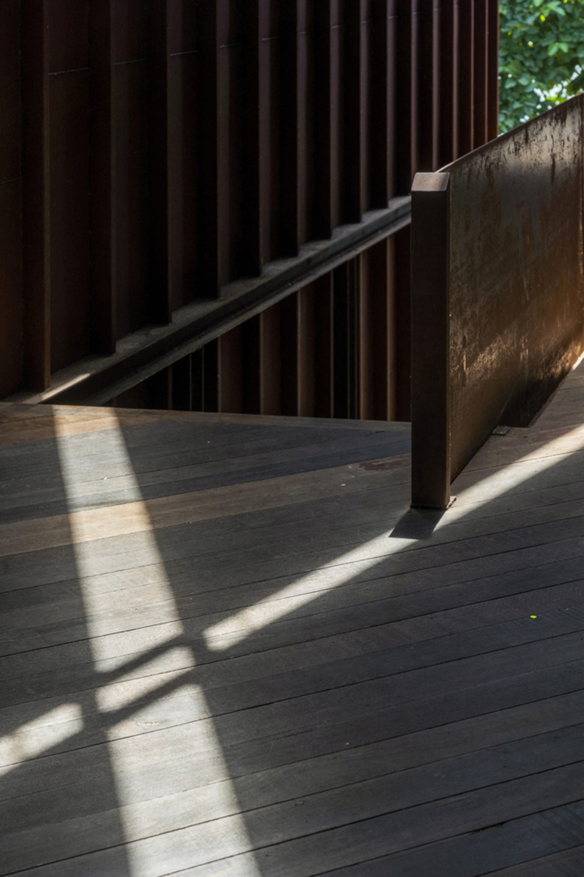 A photo of a staircase leading to a balcony with wooden stairs and sunlight coming through a window