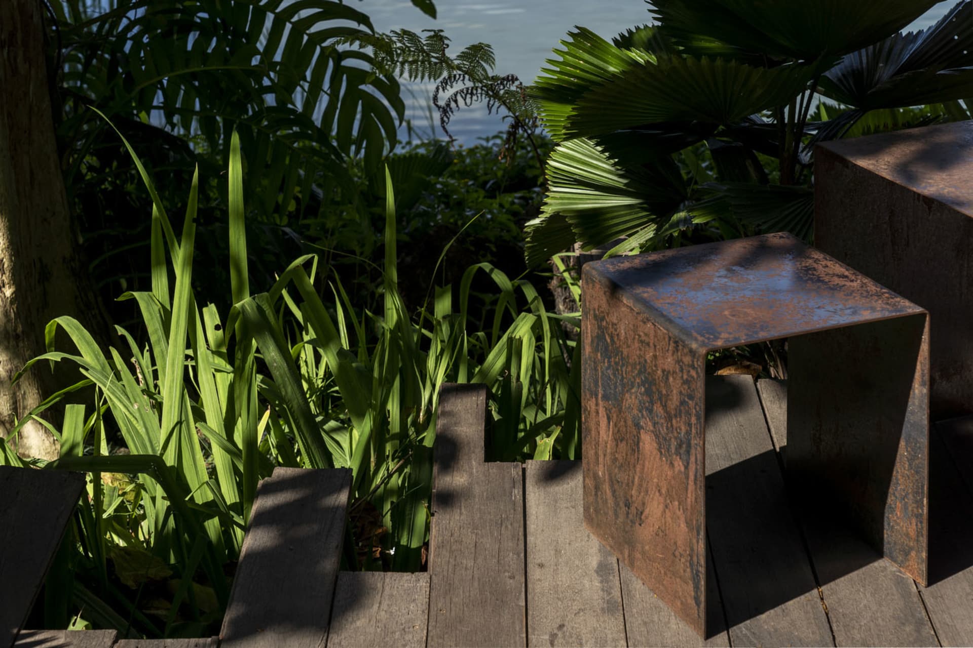 A wooden bench in a rustic outdoor patio area surrounded by plants and a staircase