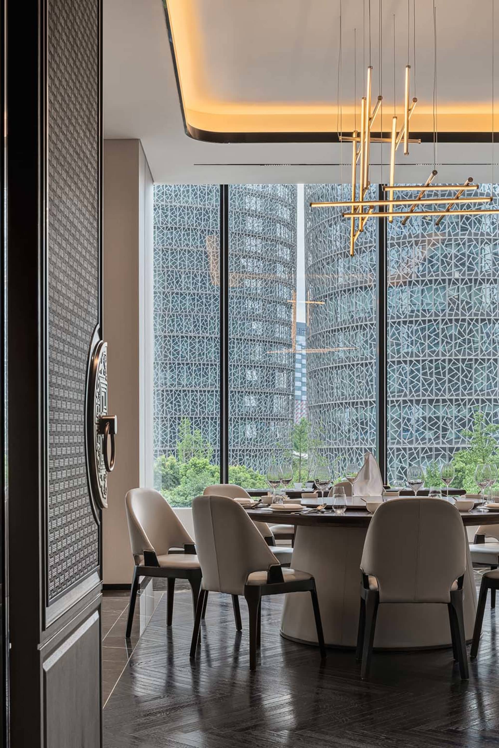 Sophisticated dining space with a large table set for a meal, surrounded by chairs and wine glasses