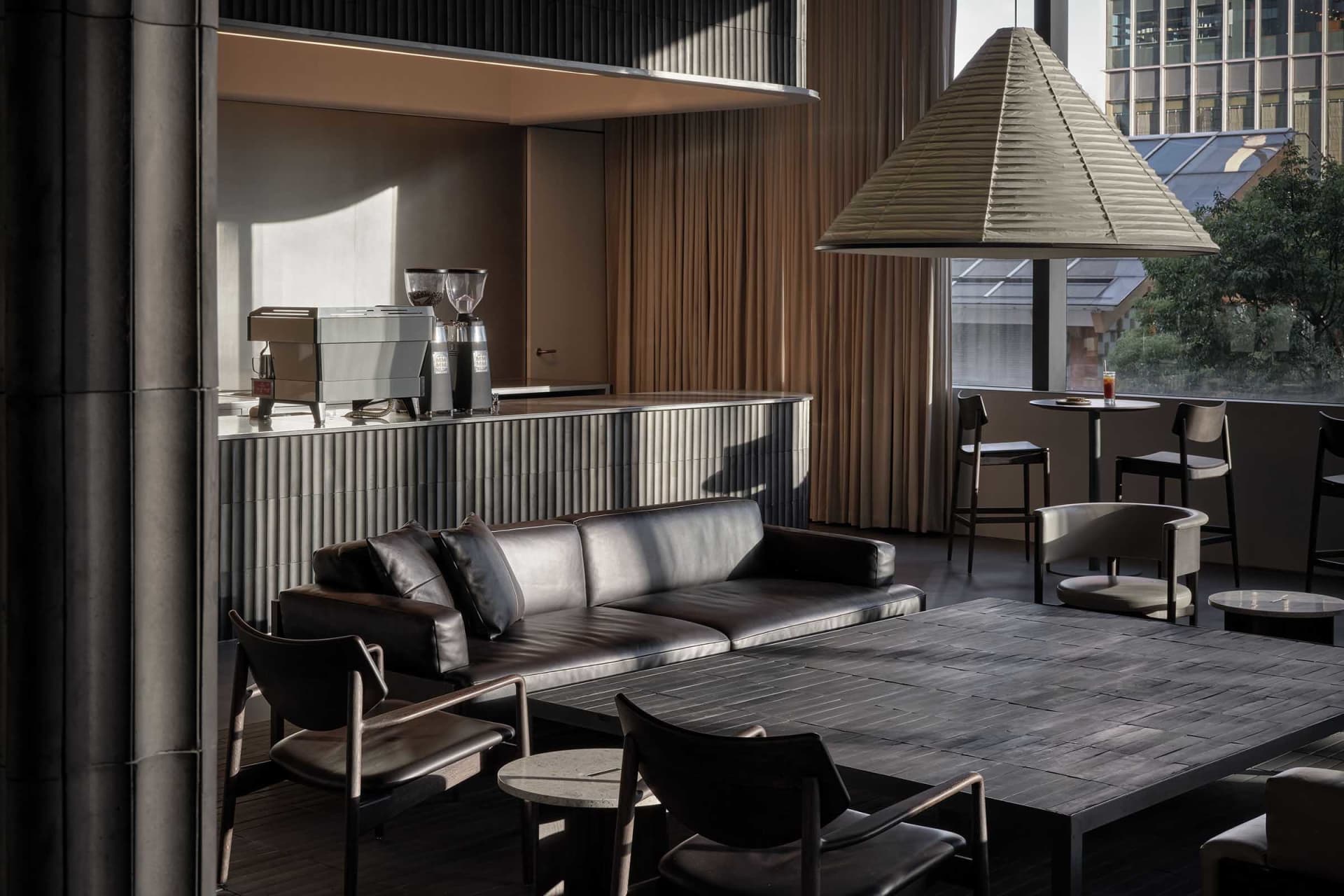 Open living area with a couch, chairs, dining table, and coffee maker, designed for relaxation and socializing