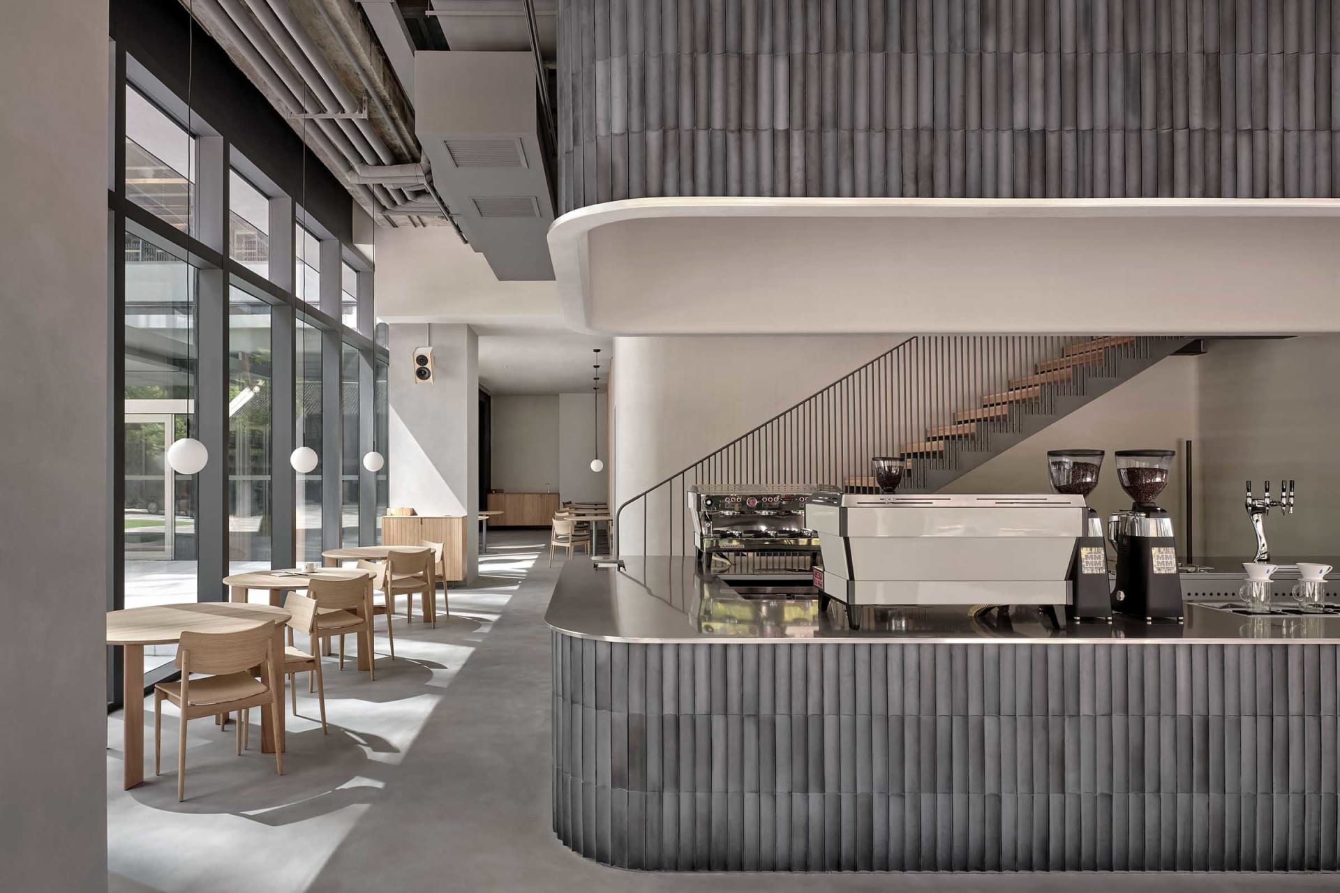 Modern restaurant kitchen with a large countertop island, sink, coffee maker, and dining table with chairs