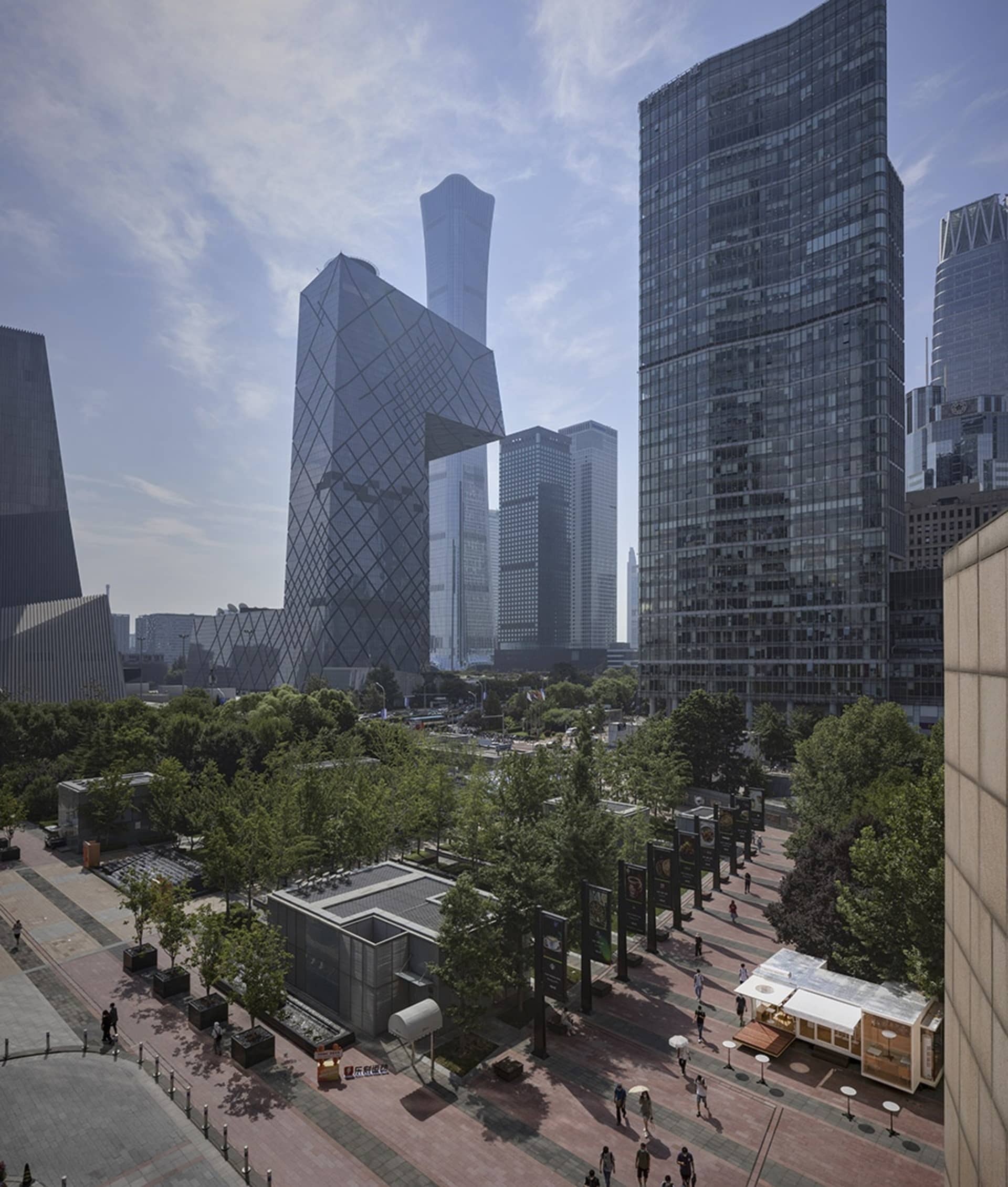 A modern city building with a glass facade, surrounded by people walking in a bustling metropolitan area