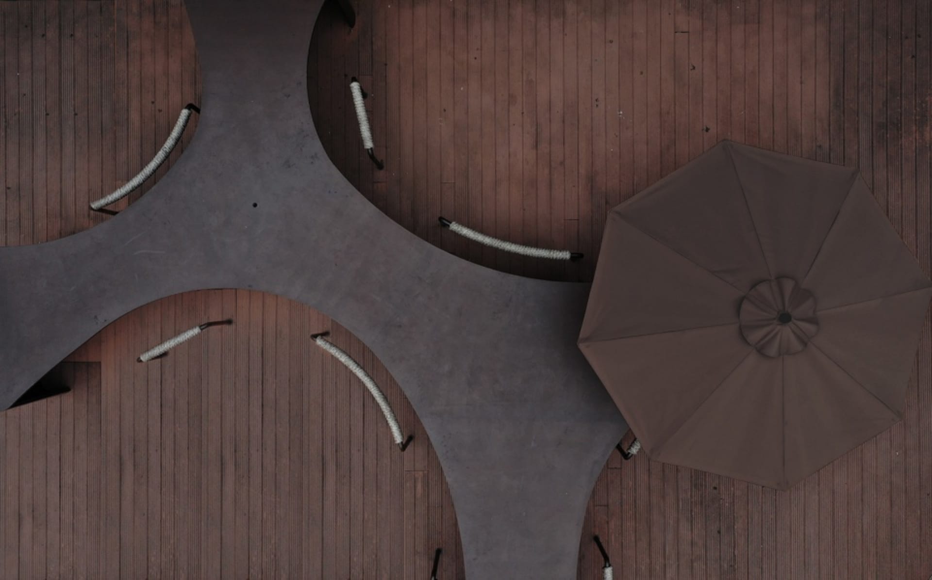 A cozy outdoor seating area with a brown fabric umbrella, surrounded by chairs, creating a warm and inviting space for relaxation and socializing