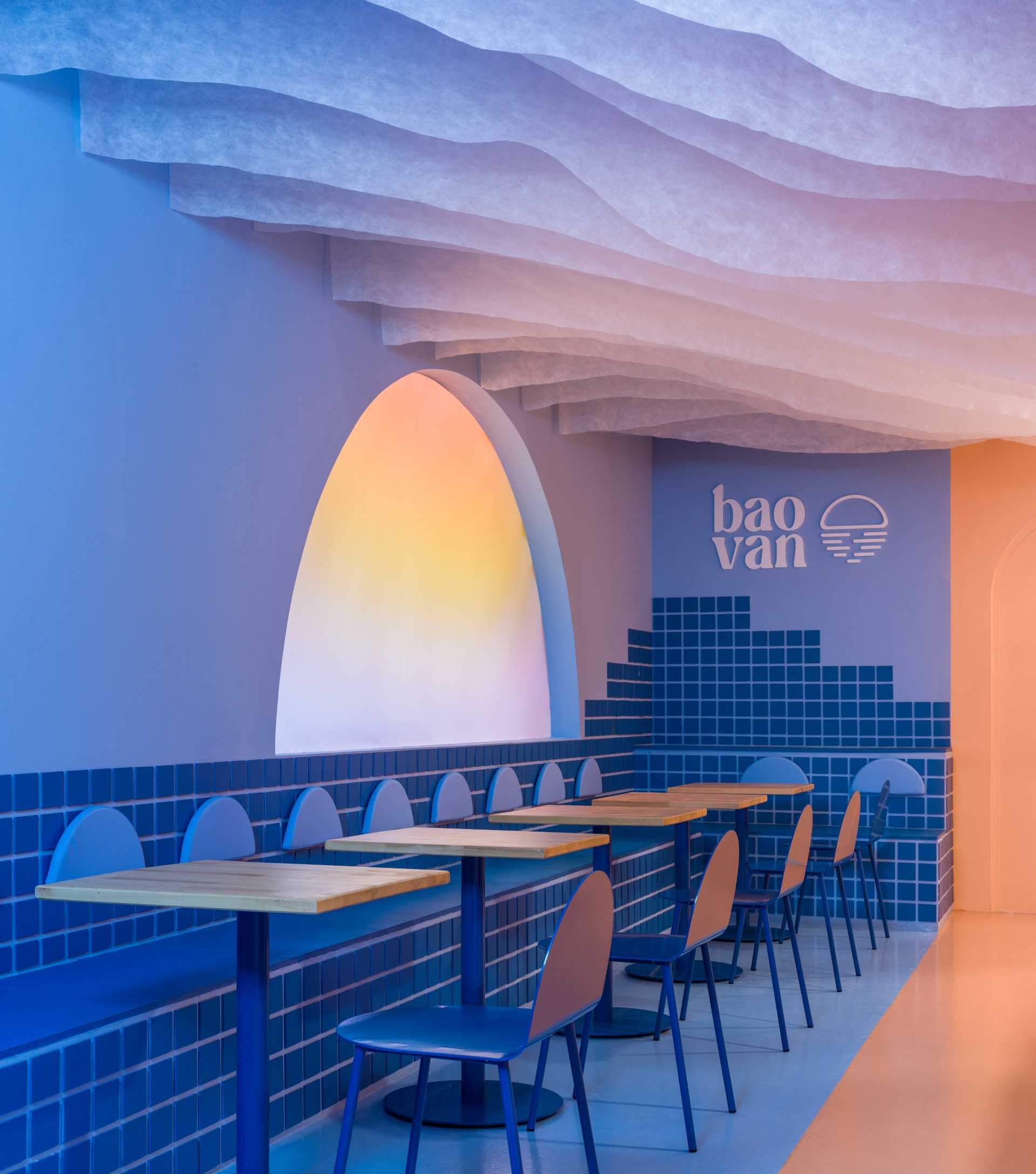 A modern restaurant interior with blue walls, dining tables, chairs, and cups, creating an inviting atmosphere