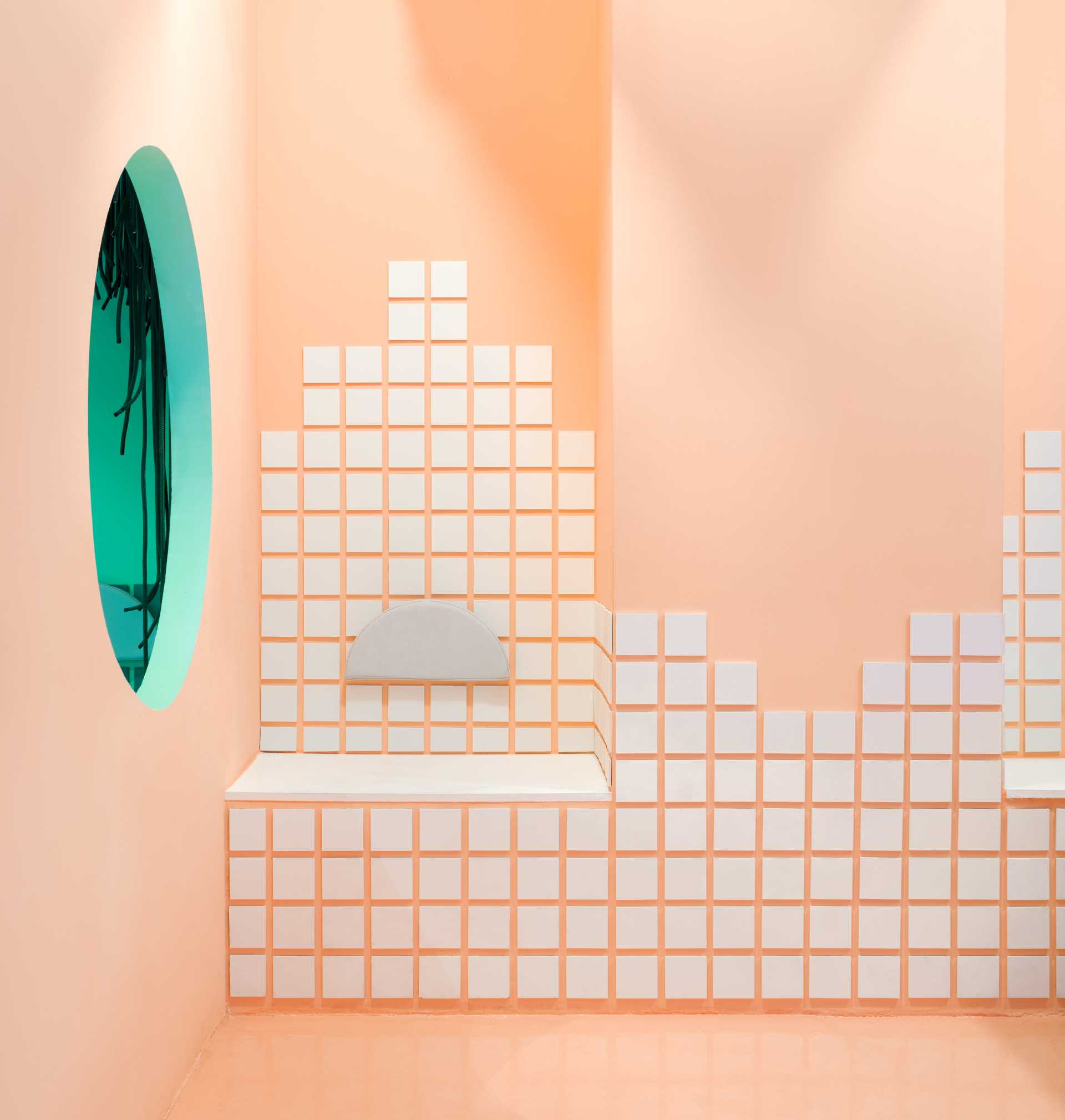 Pink bathroom with white tiles on the walls and floor, featuring two sinks and a bench in a minimalist design