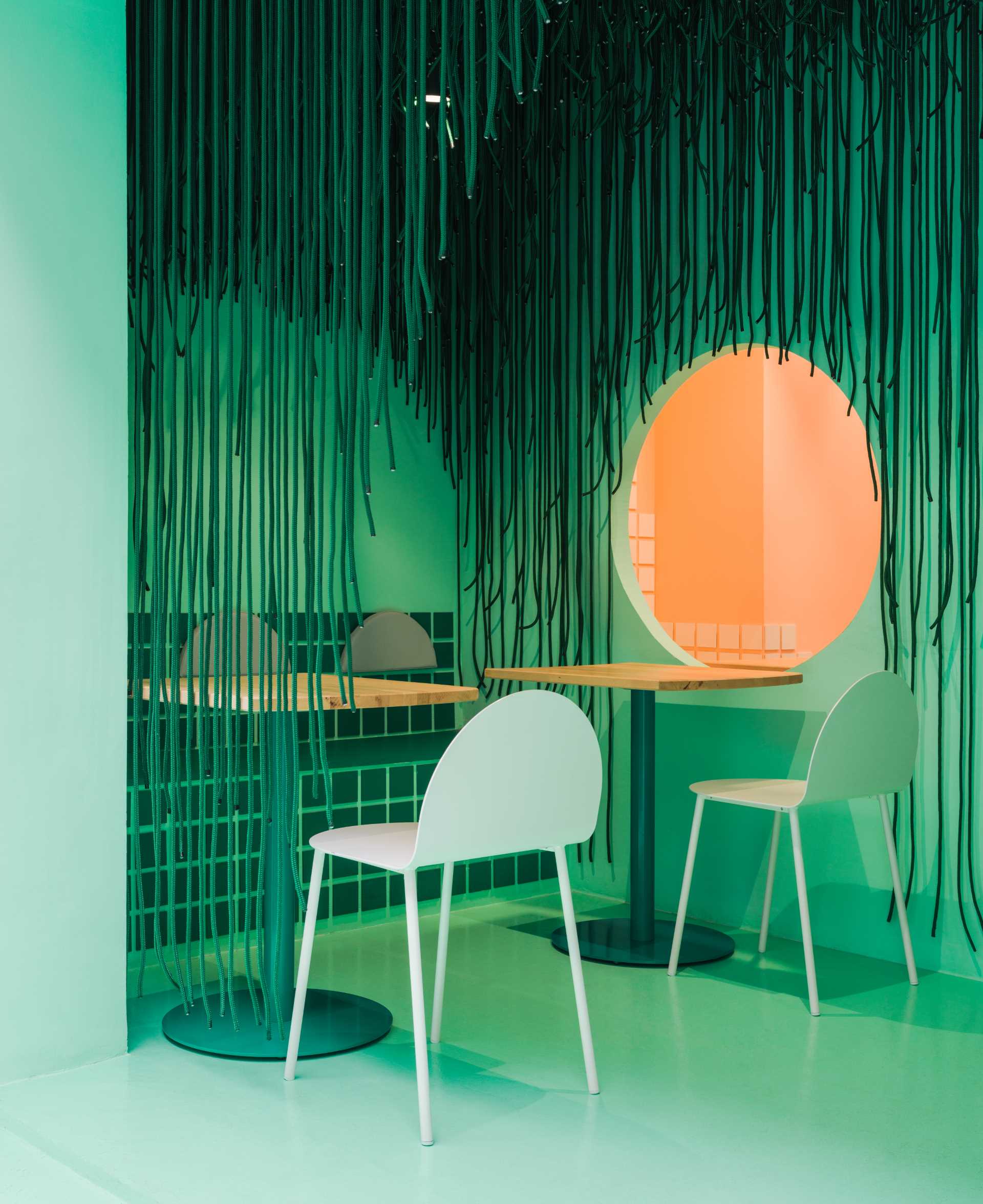 A calm and inviting dining area with a green and white color scheme, featuring modern minimalist chairs and a central dining table