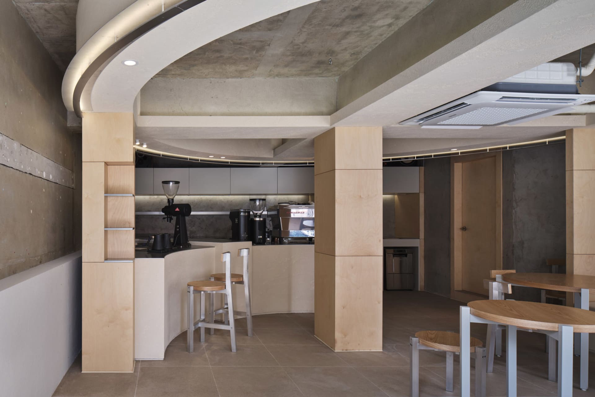 木質牆面與地板的開放式廚房餐廳空間，設有兩張餐桌、椅子與咖啡機