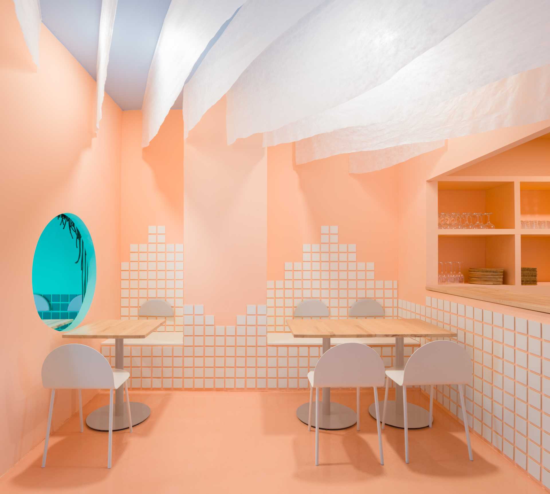 Warm and inviting restaurant interior with pink walls, white chairs, and a tiled pattern on the walls