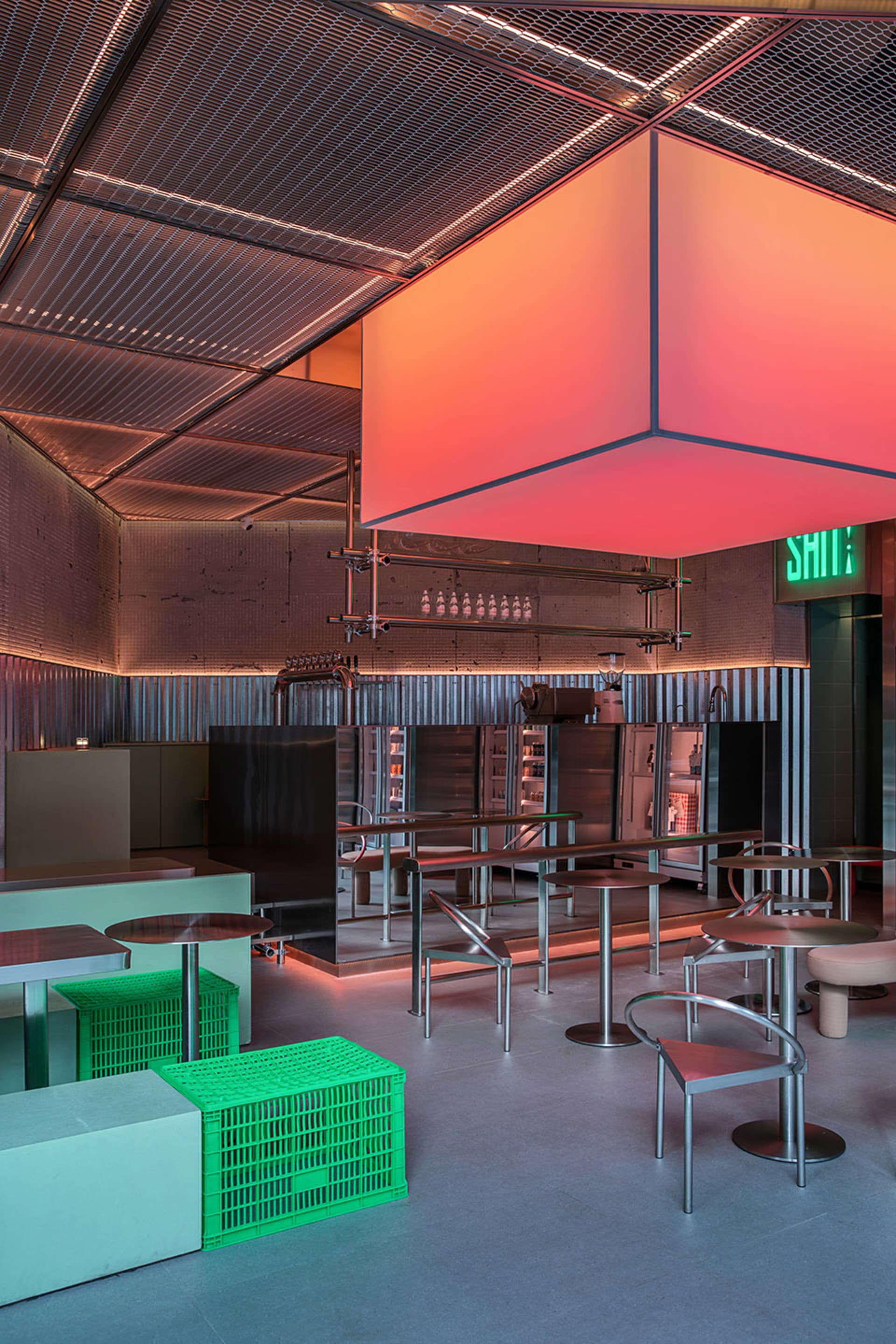 Modern industrial restaurant interior with metal walls, multiple dining tables, and comfortable seating for guests