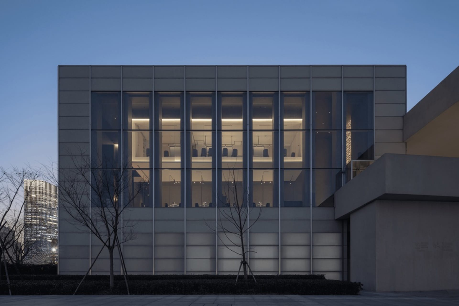 A concrete building with large windows on each side, allowing natural light to enter and creating a bright and inviting environment