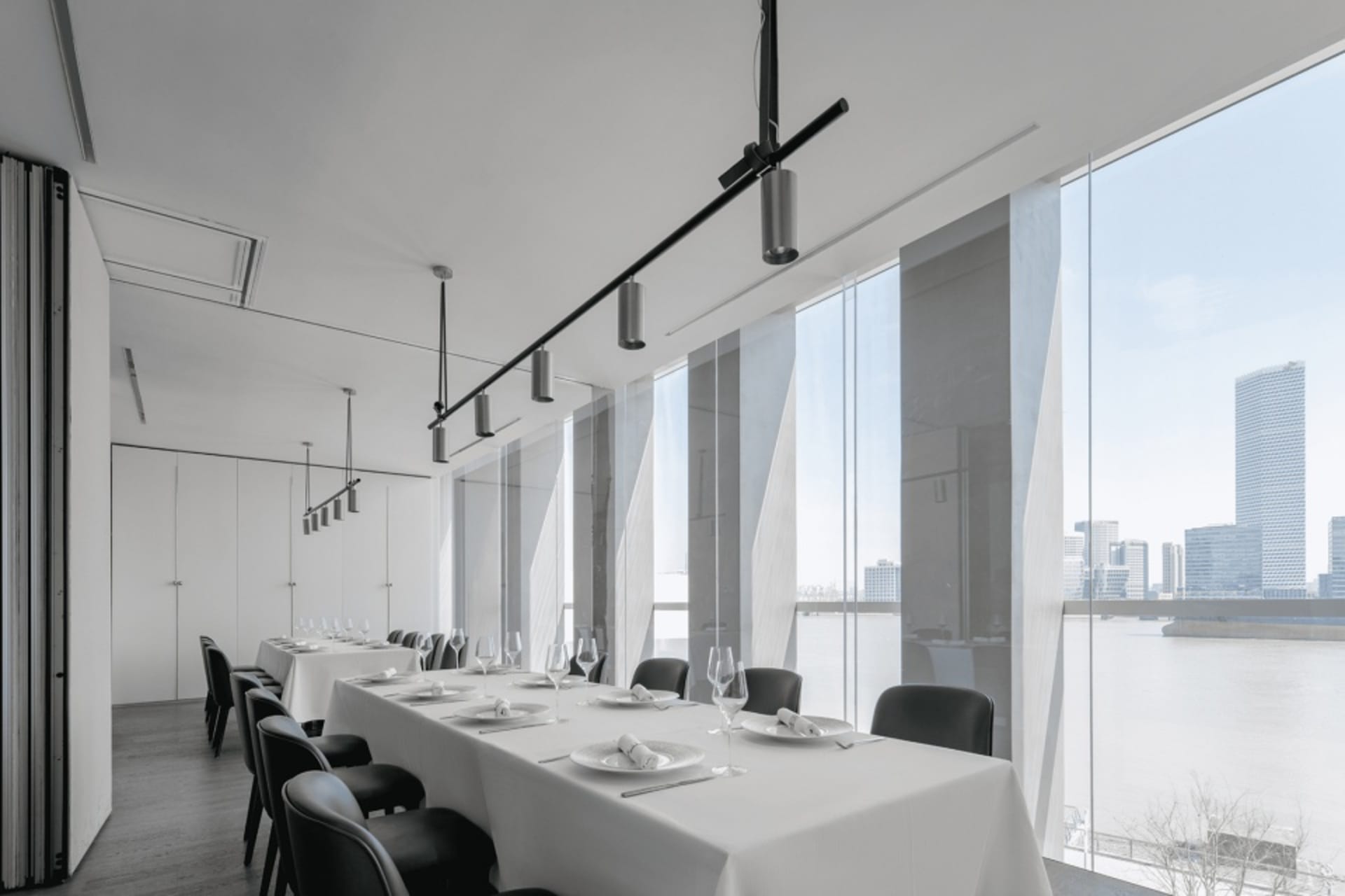 Formal dining area with a large table set for dinner service, surrounded by multiple chairs and wine glasses