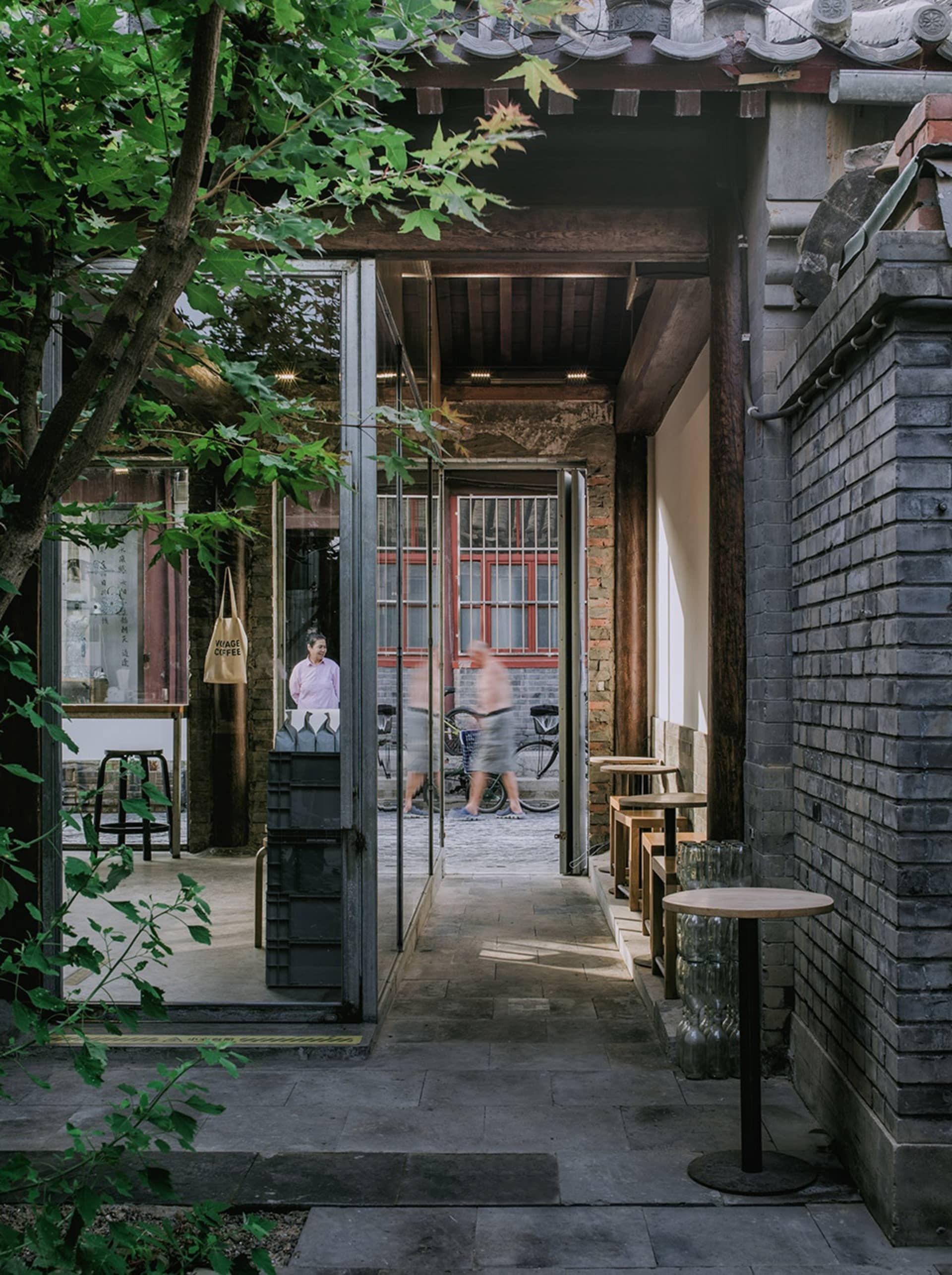 A home interior with a dining table and chairs, cups scattered around, and two people standing near the doorway