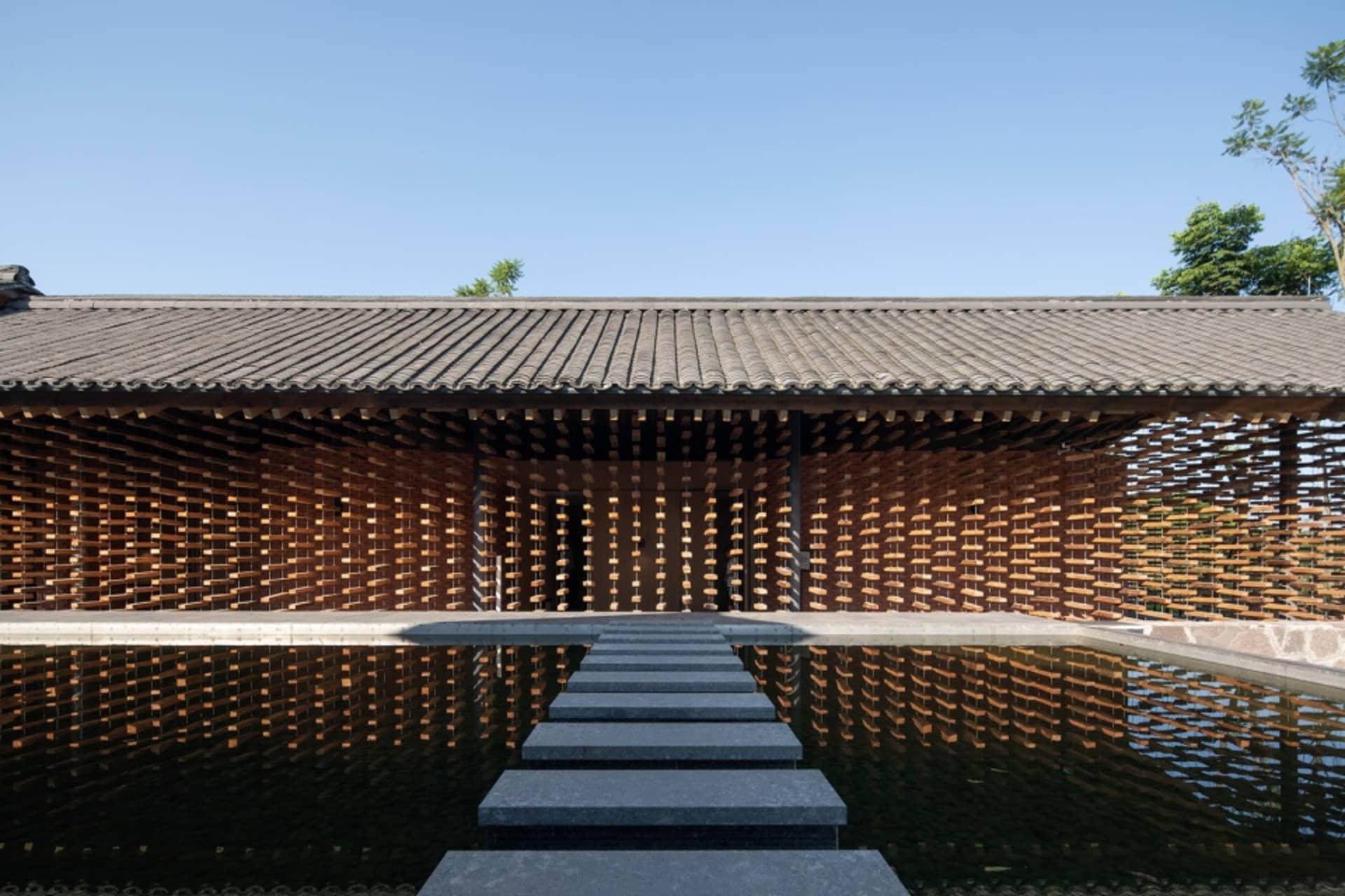 Asian-style building with a wooden structure and a reflective pool in front of it, featuring a unique design with a combination of wood and stone elements