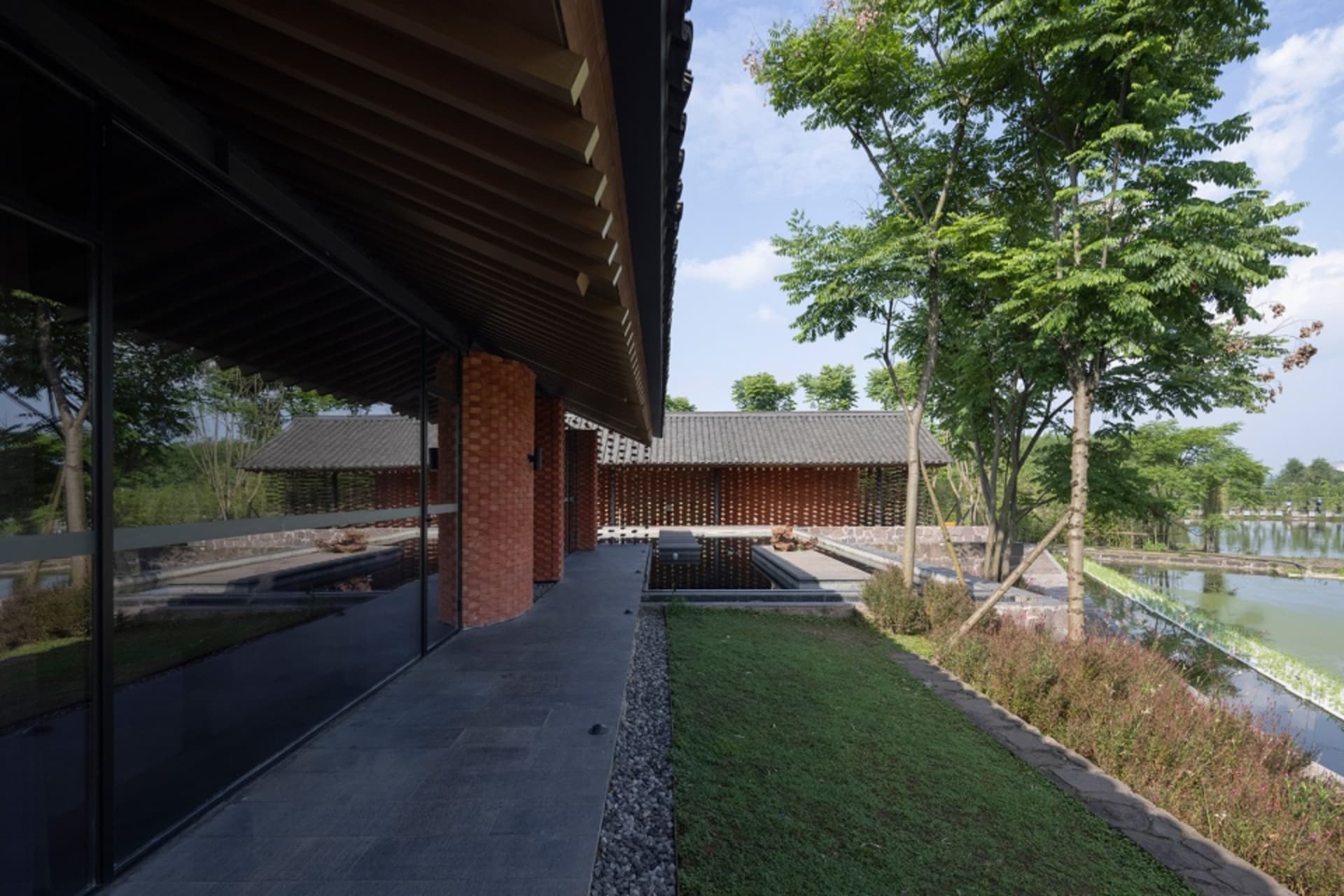 A traditional Asian-style house with a courtyard surrounded by two brick houses, a pond, and natural sunlight