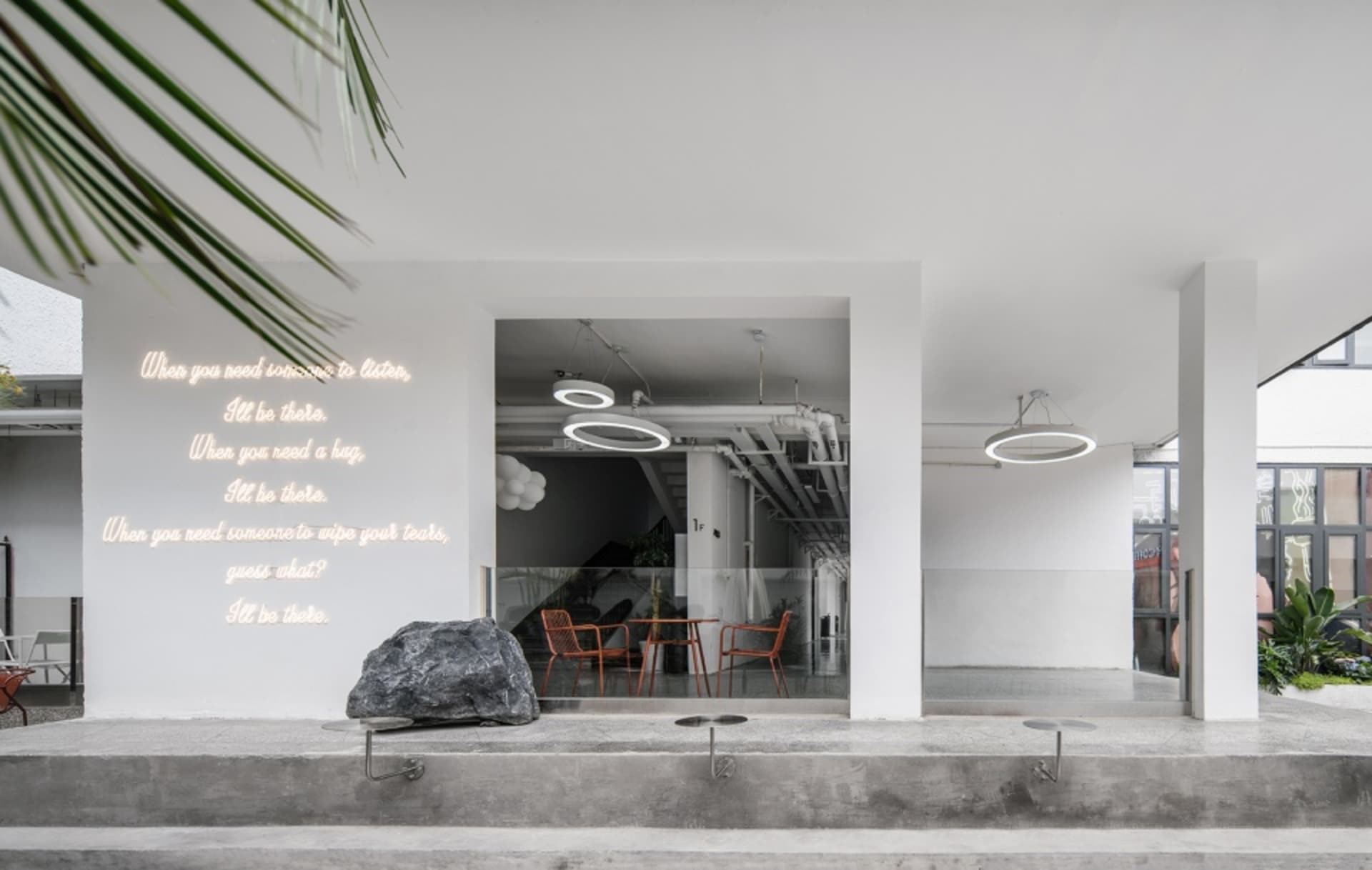 A modern cafe with exposed walls featuring writings, potted plants, and warm lighting