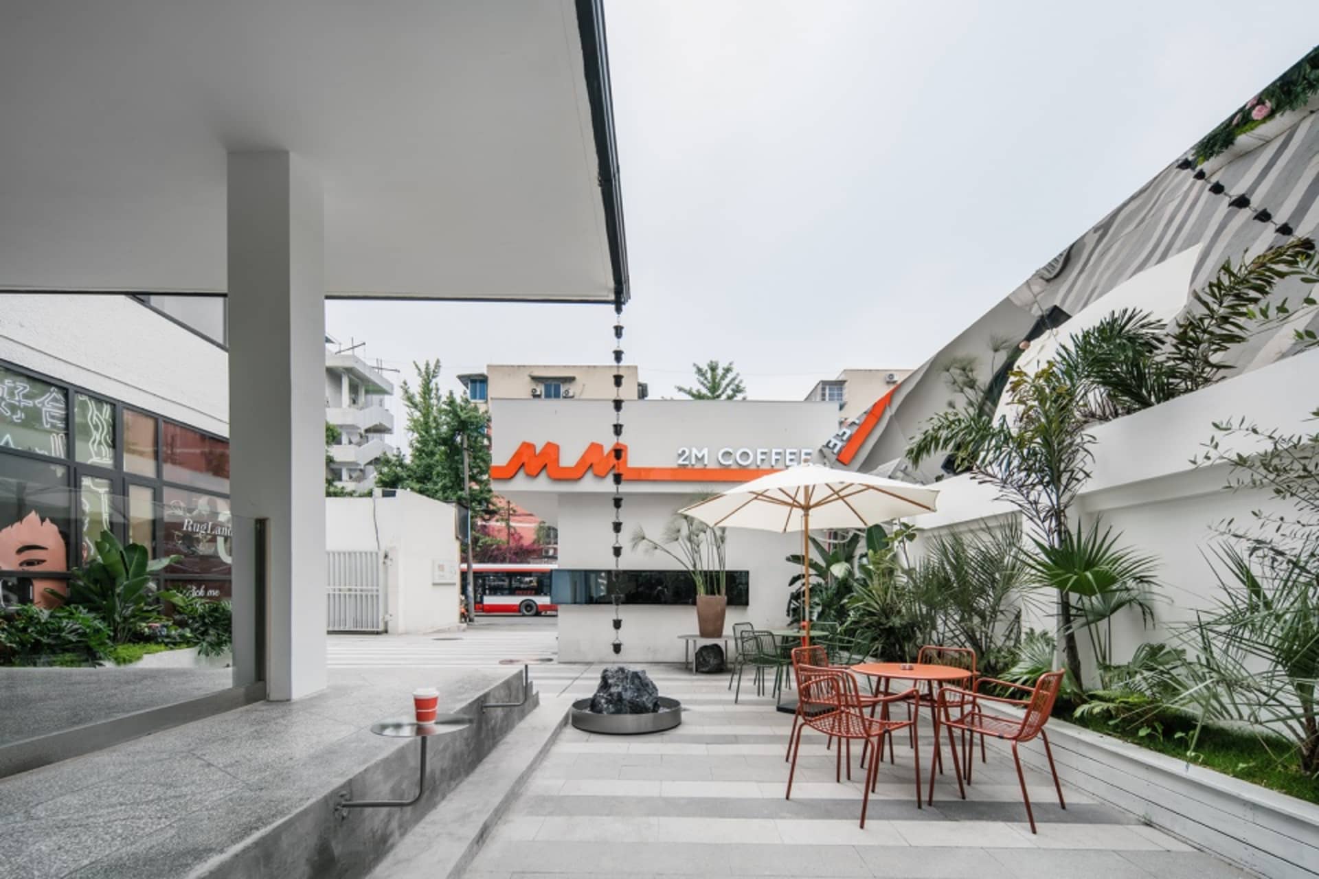 現代咖啡店配有大片窗戶、椅子、餐桌與盆栽植物，營造明亮當代氛圍