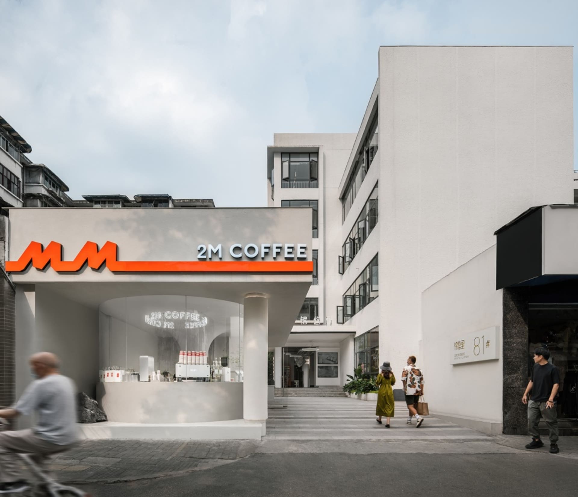 熱鬧的城市街道上，一家現代咖啡店擁有白色外牆與玻璃立面，周圍環繞著行人