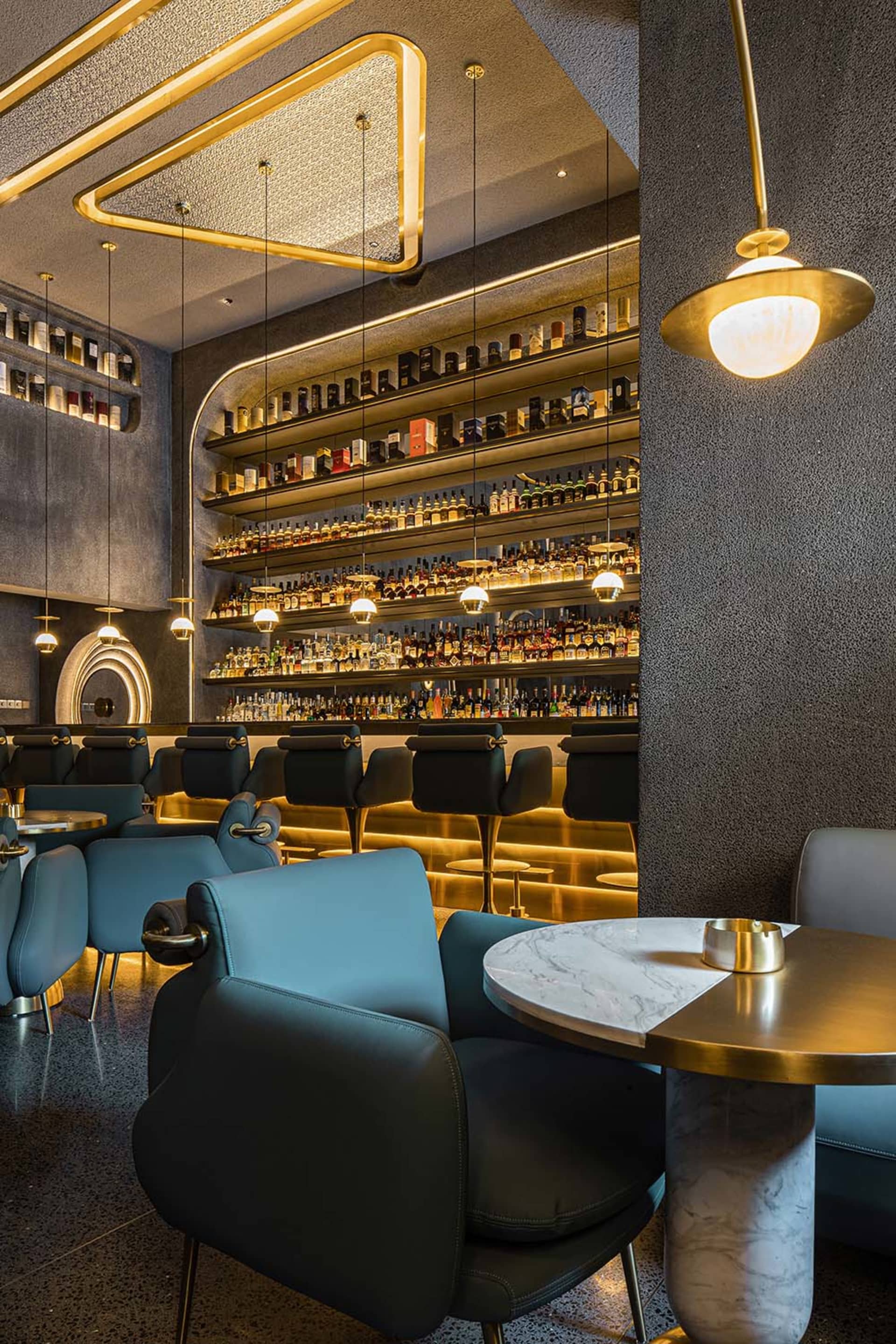 A cozy bar area with a liquor display behind the counter, comfortable seating, and a social atmosphere