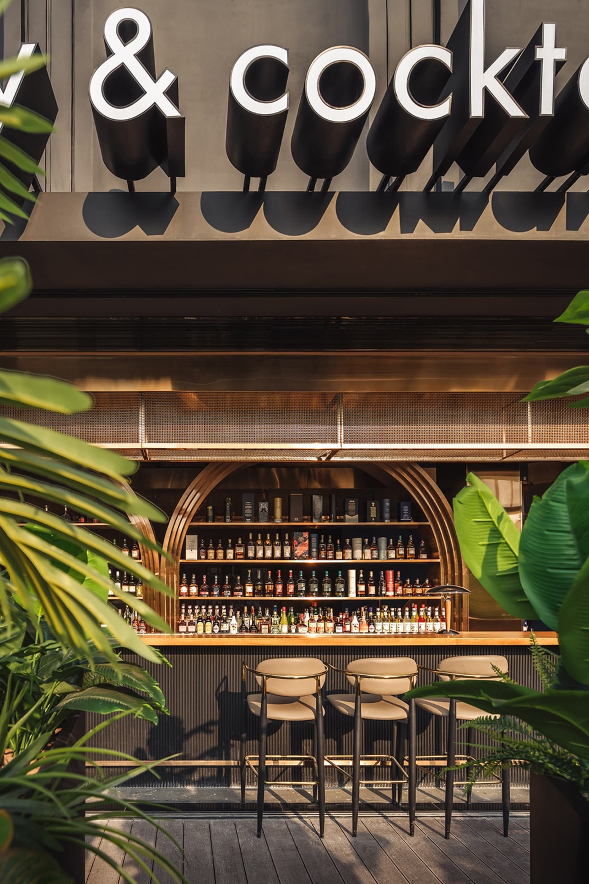 Inviting bar area with a wooden countertop, chairs, and bottles displayed, set in a restaurant