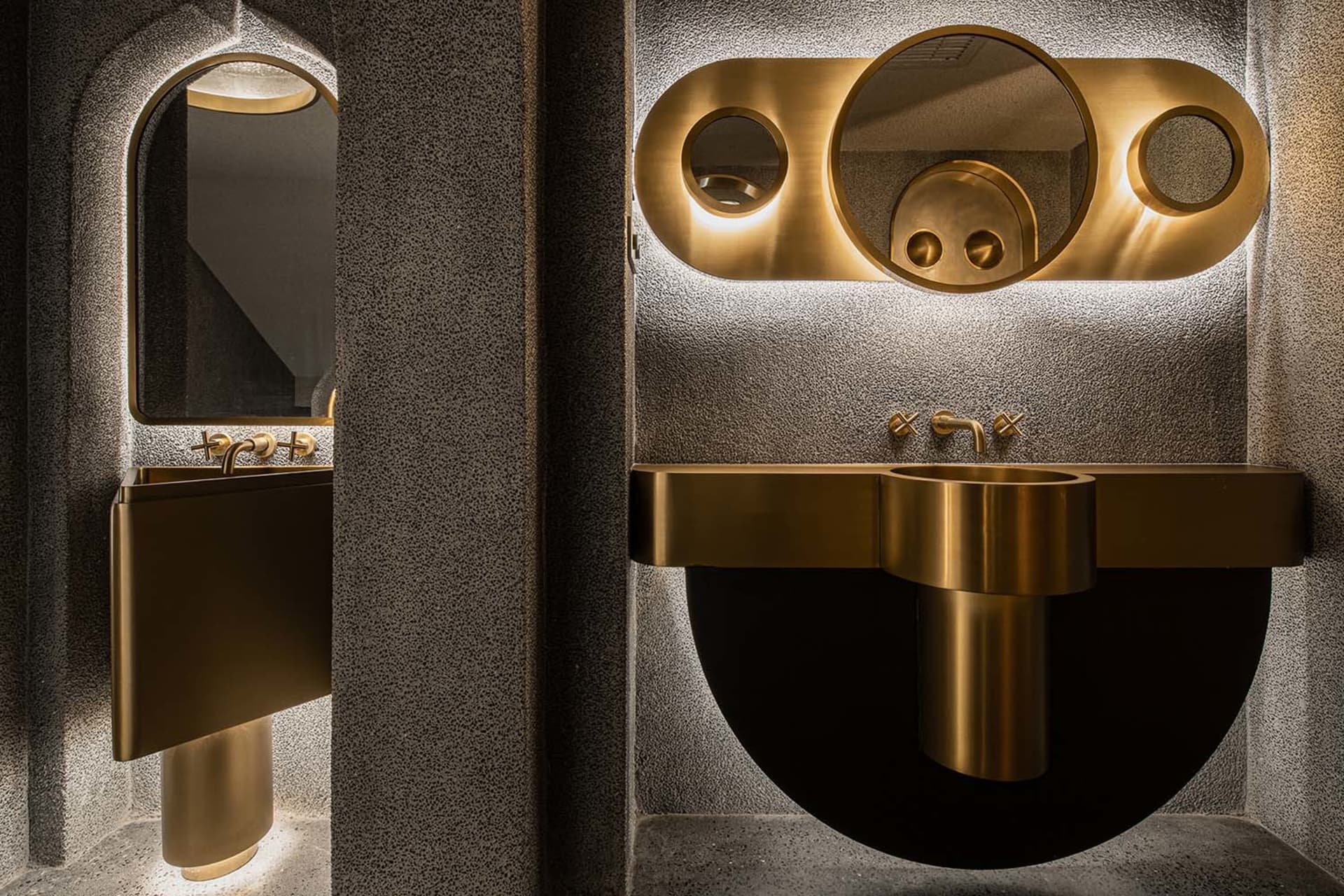 Two modern bathroom sinks with gold fixtures and large mirrors in a well-lit public restroom