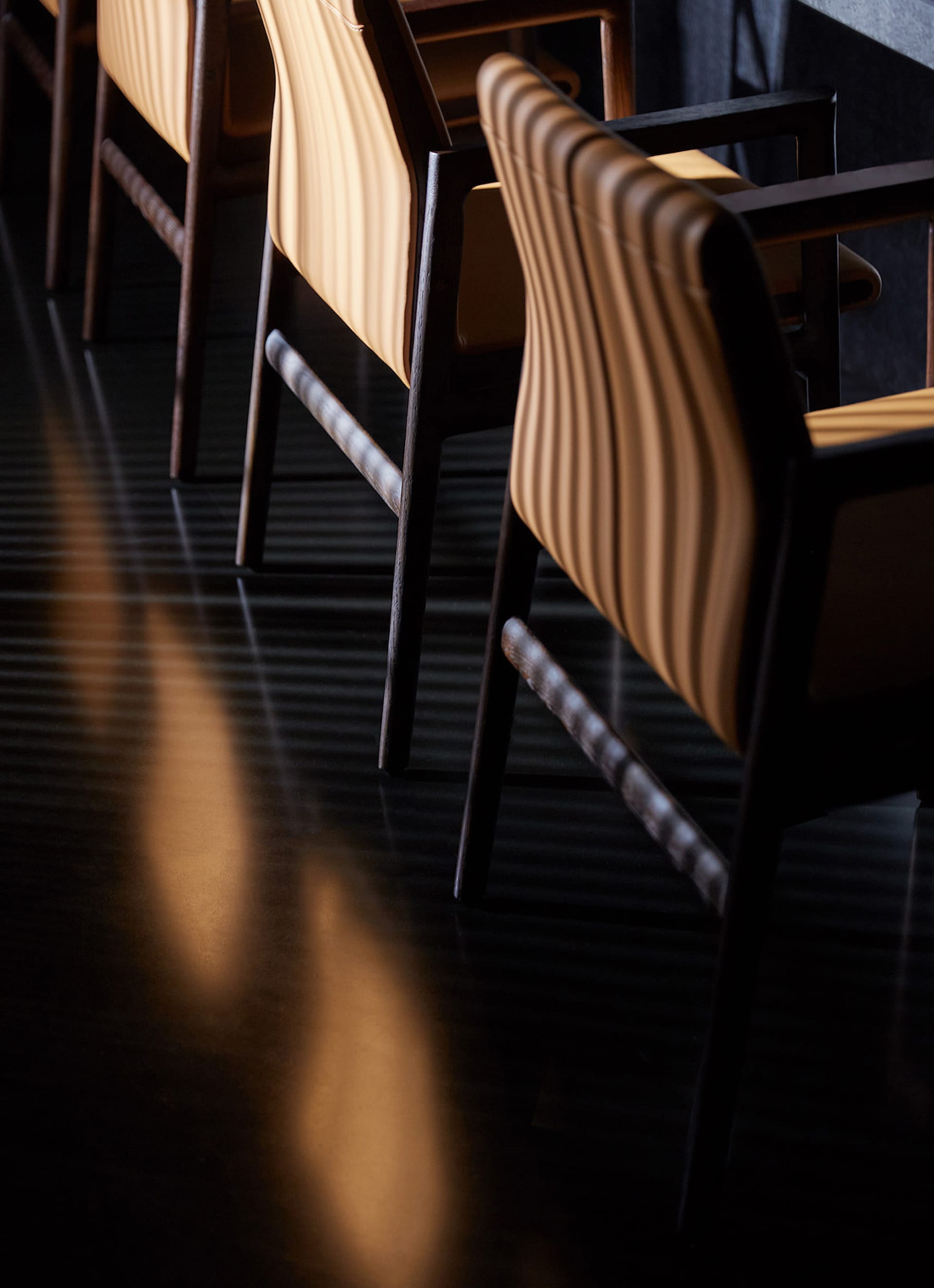 Darkened dining area with several wooden chairs arranged around a table, creating an intimate atmosphere