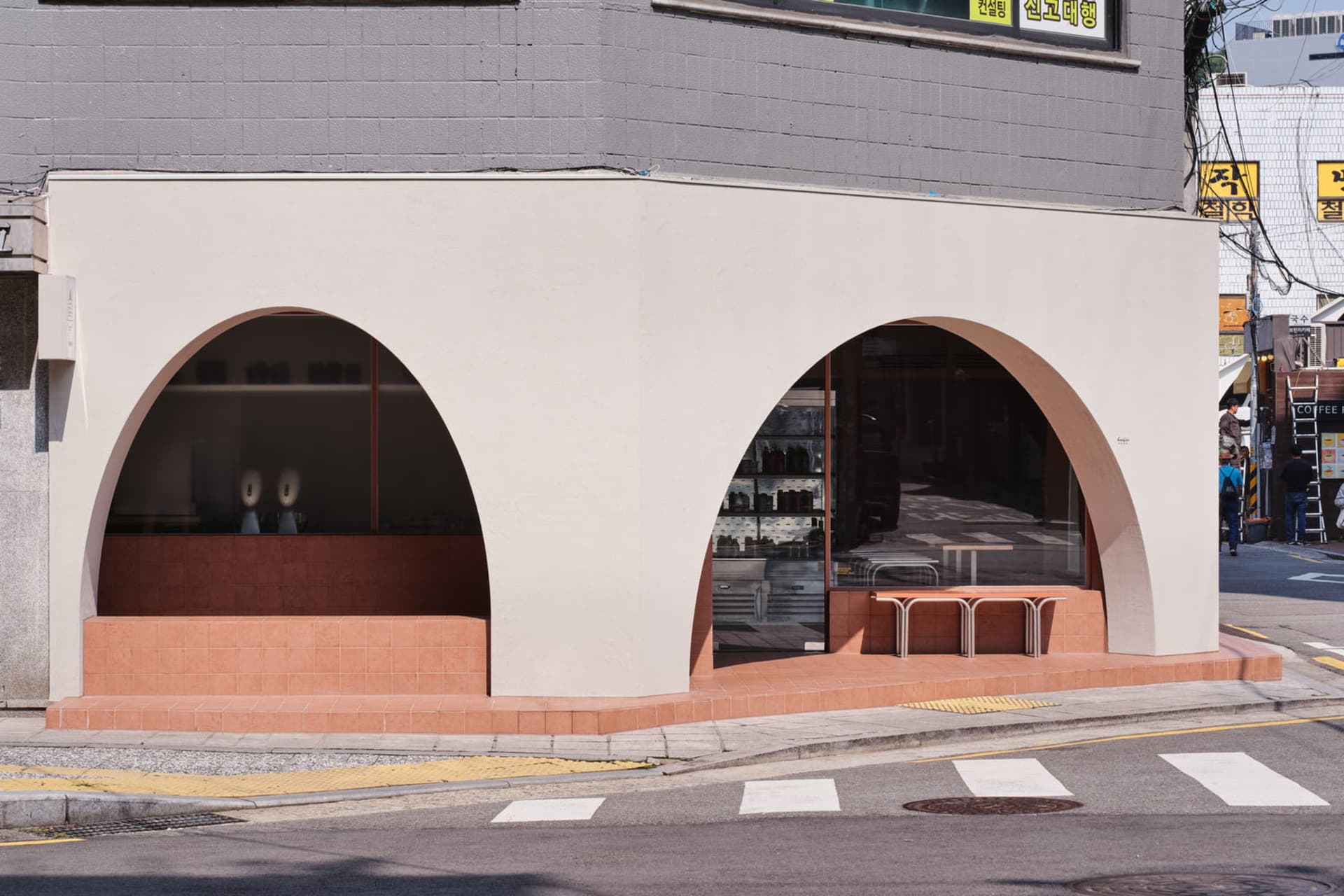 A modern building with concrete arches and a dining area with chairs and bottles, conveying a contemporary and inviting atmosphere