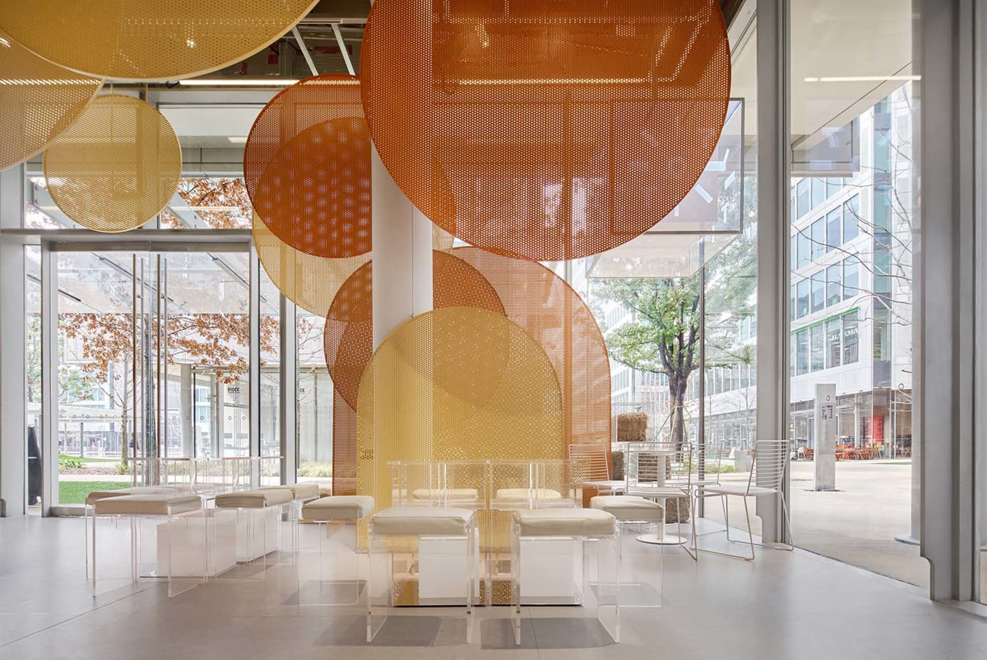 A bright and inviting indoor space with multiple white chairs and tables arranged for socializing and dining, with natural light coming through windows