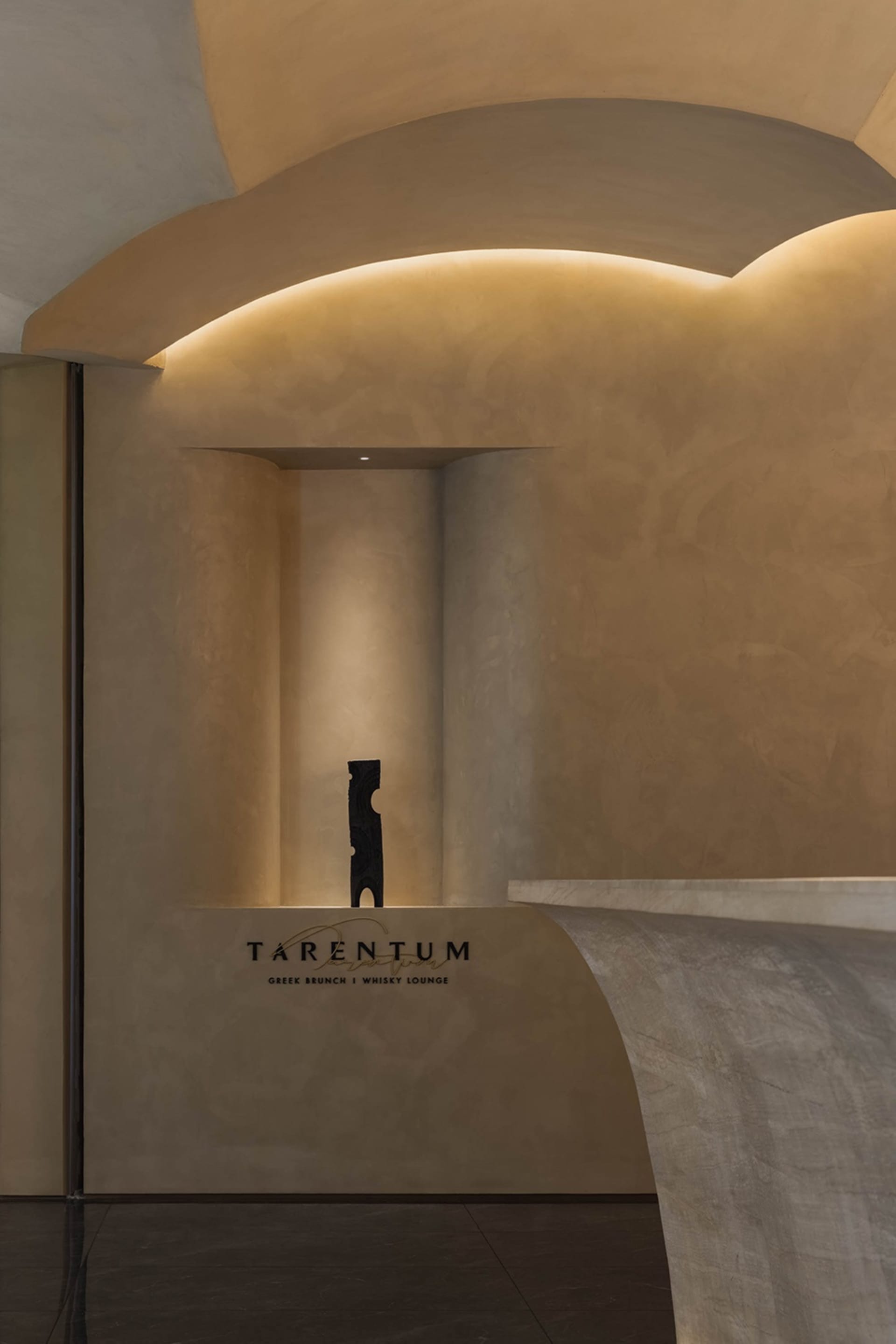 A modern art gallery with a black sculpture on a pedestal surrounded by artwork-adorned walls