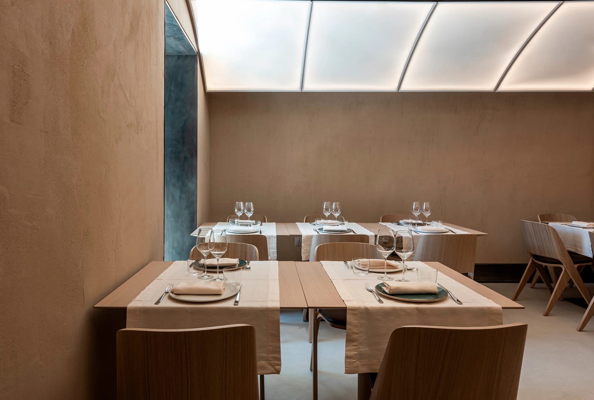 A restaurant dining area with white tablecloths, wine glasses, and comfortable seating, creating a clean and inviting atmosphere