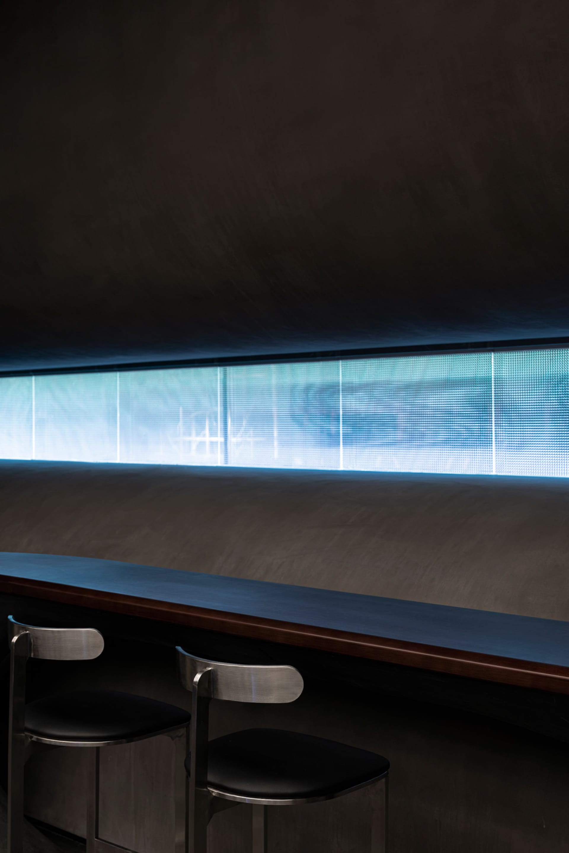 A professional office space with a long wooden table and metal chairs, a bench, and a modern atmosphere