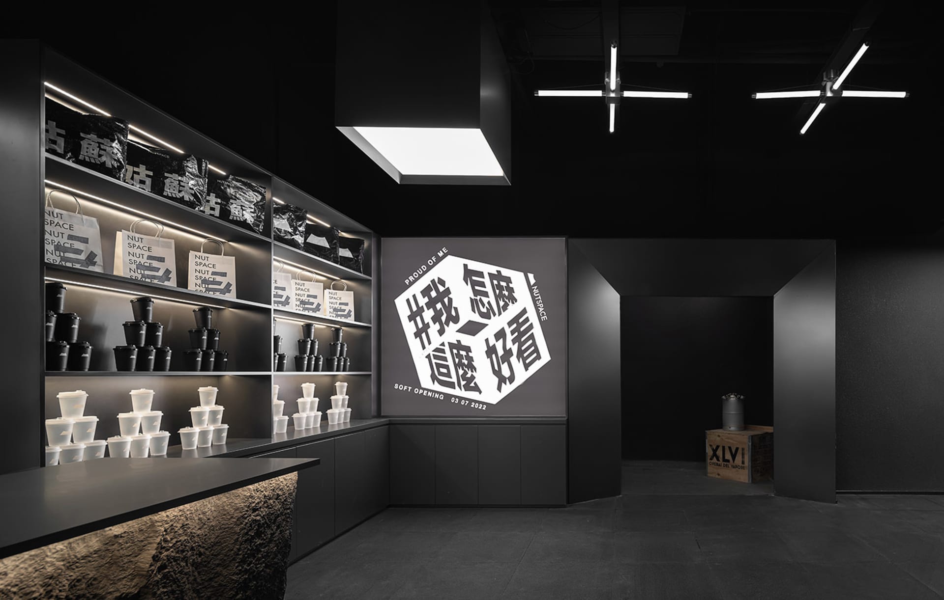 A dark and intimate Asian restaurant interior with black decor, featuring a wall with Chinese writing and a countertop with several cups