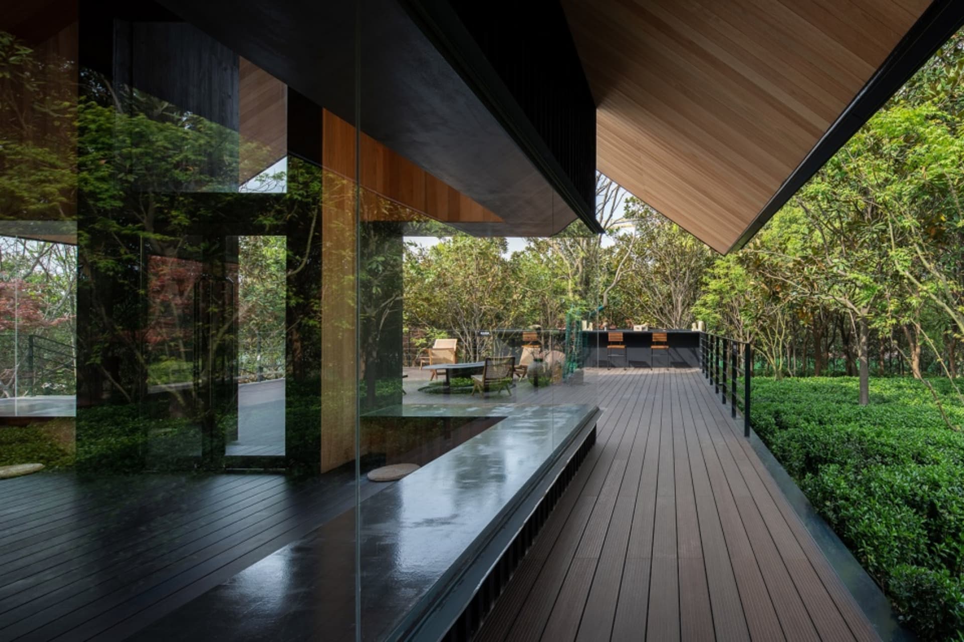 Cozy modern living area with a glass wall, dining table, and benches, surrounded by natural light and a view of the surrounding trees