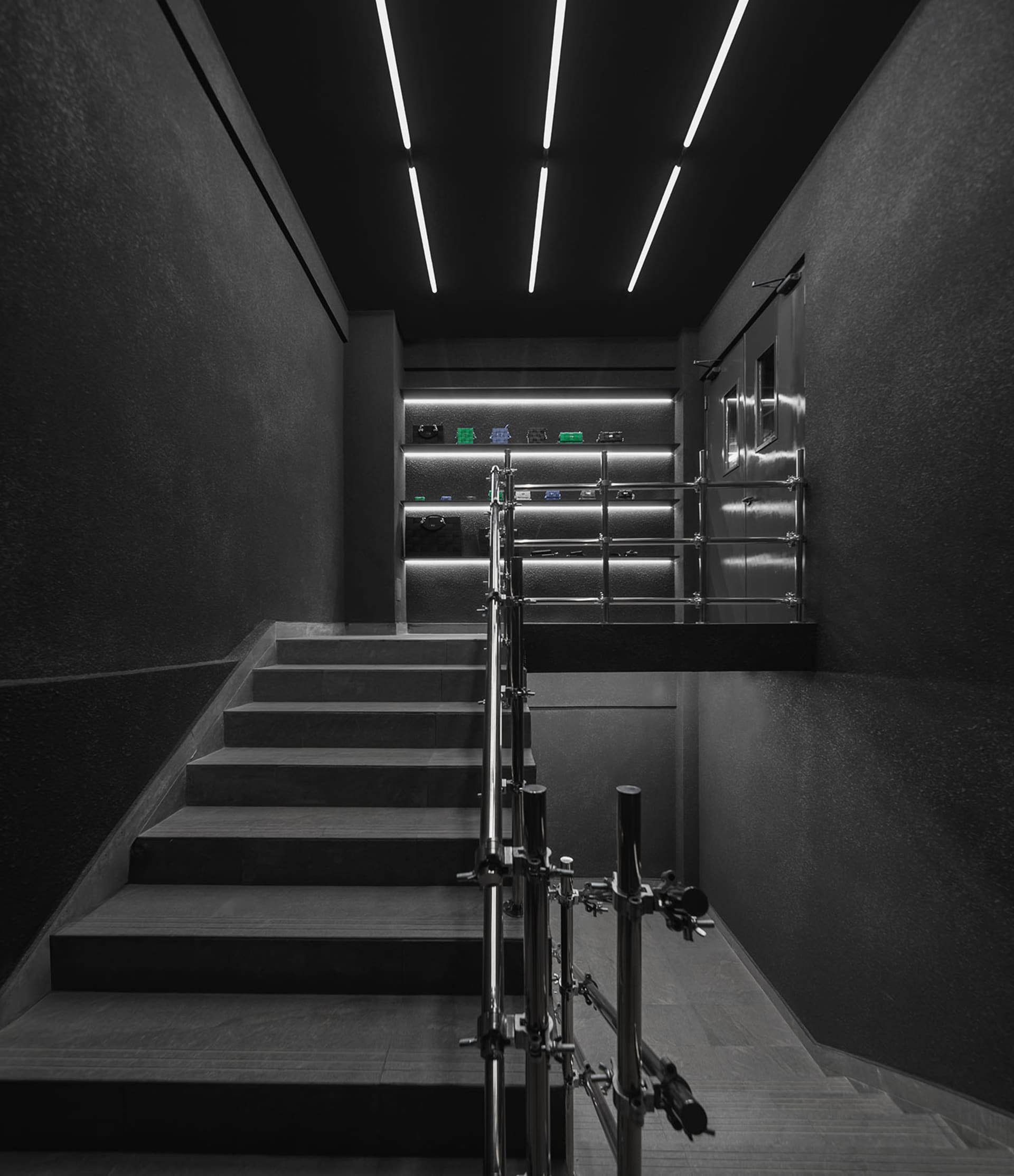 A darkened stairwell with metal stairs and two sets of stairs leading to different levels