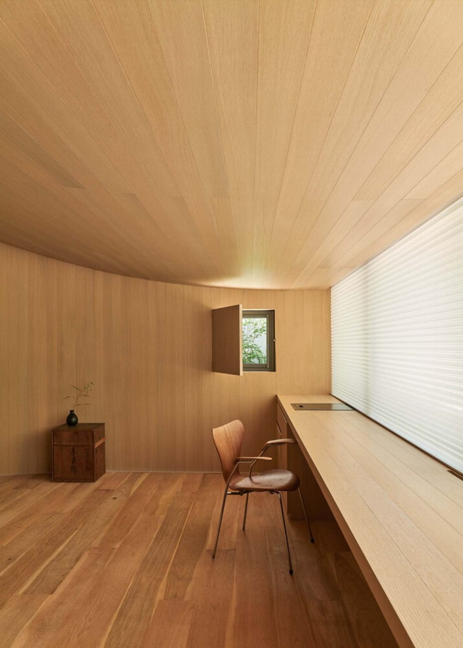 Warm and inviting office space with wooden floors and walls, featuring a desk, chairs, and a potted plant