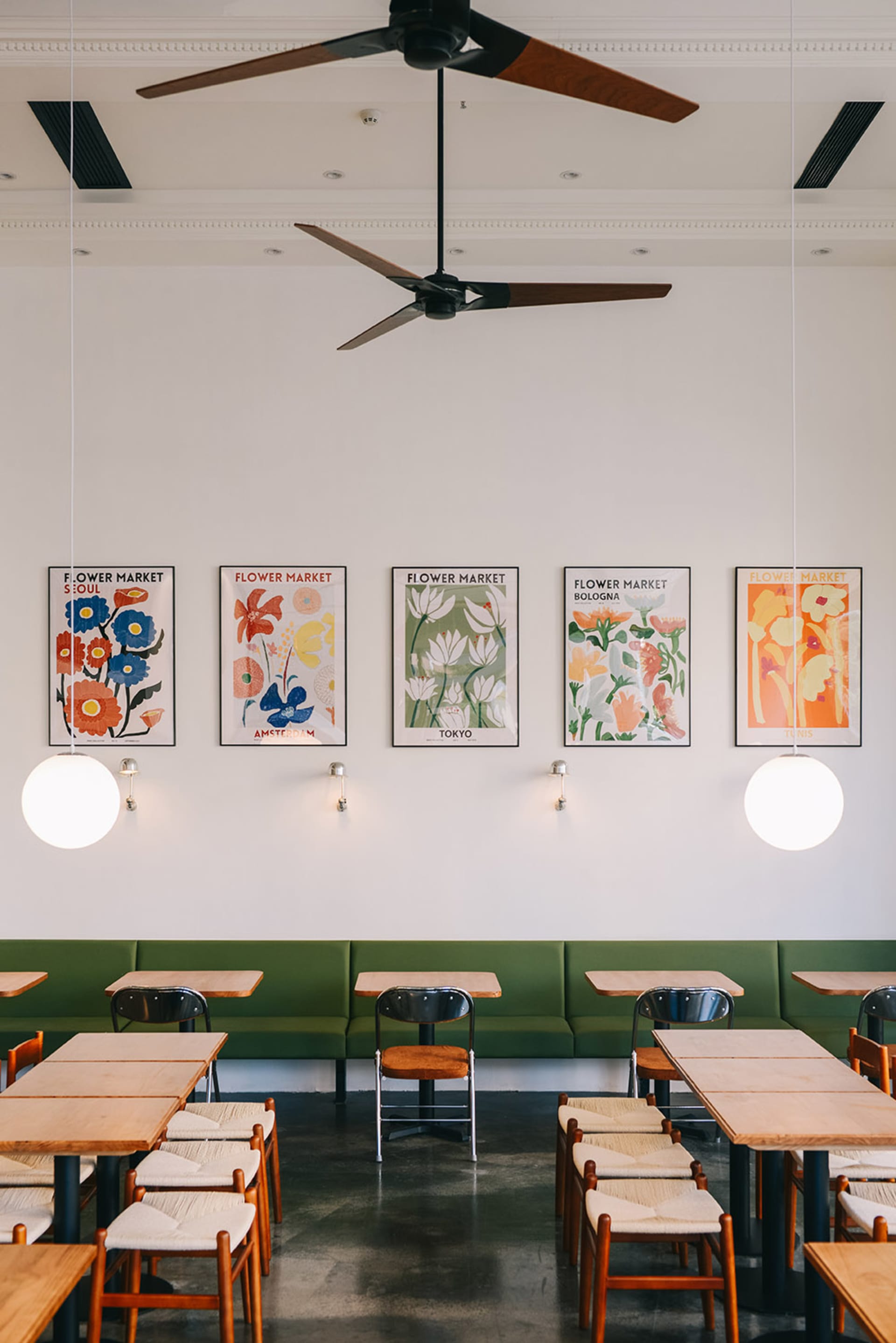 Modern restaurant dining area with wooden furniture, green accents, and potted plants, featuring multiple tables and benches