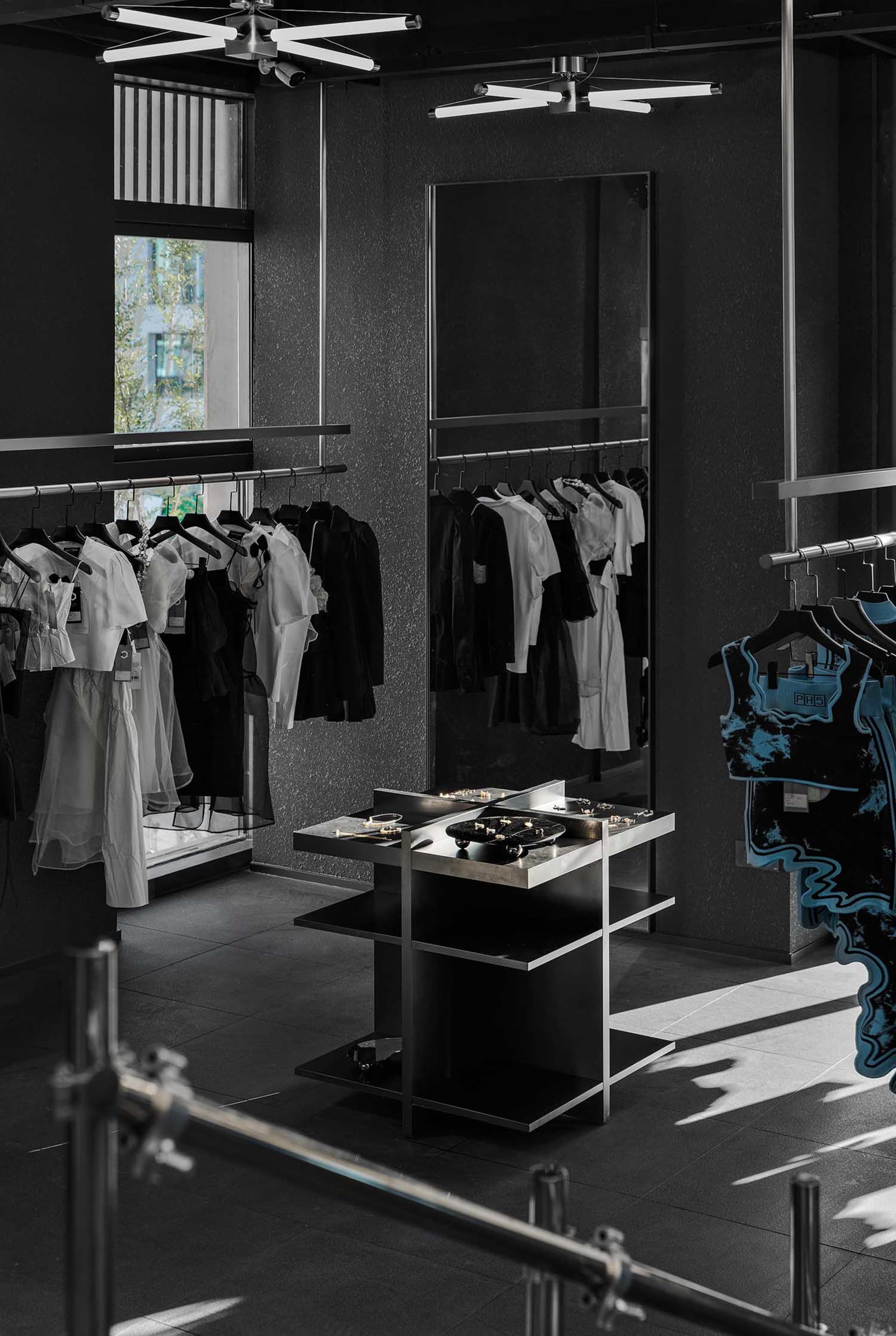 A modern retail space with a black and white color scheme, featuring dresses and handbags on display, with warm and inviting lighting